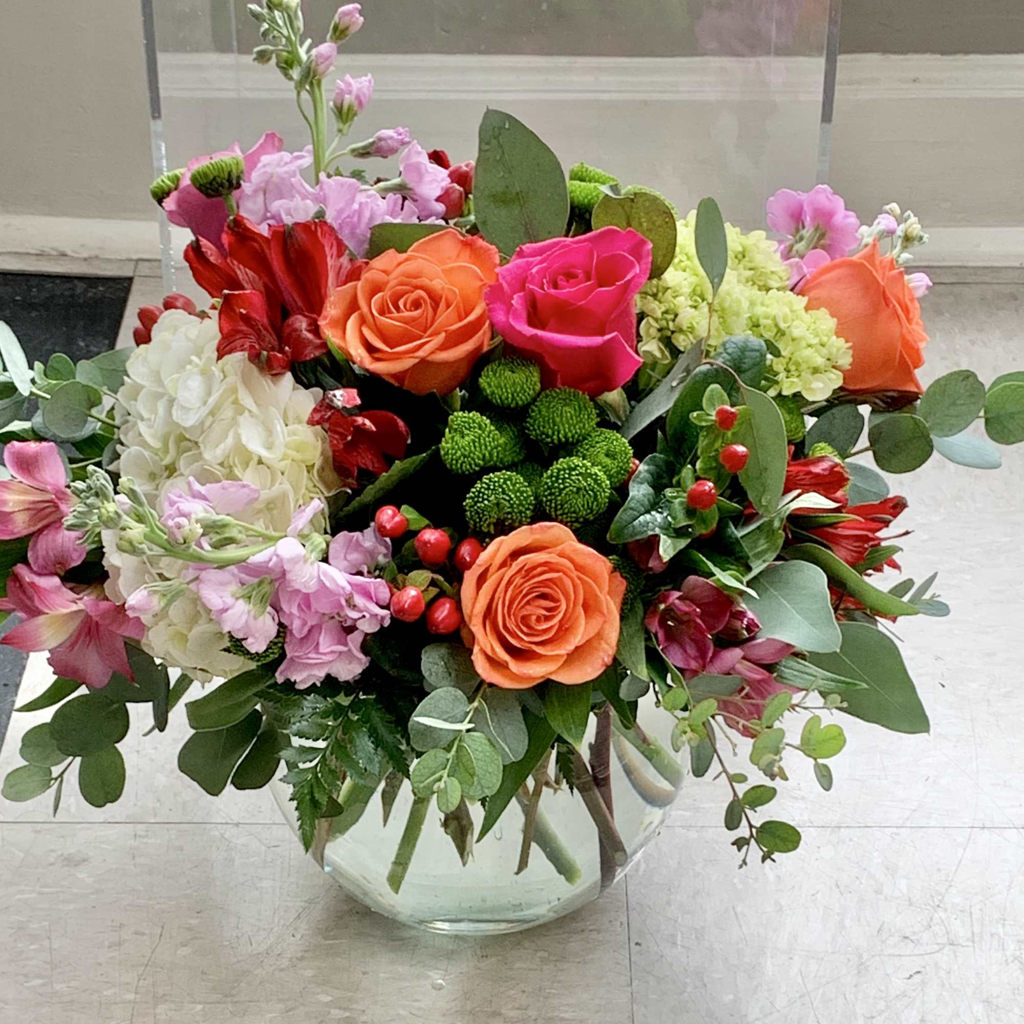Mixed bouquet of roses, hydrangea, and pink flowers in a glass vase