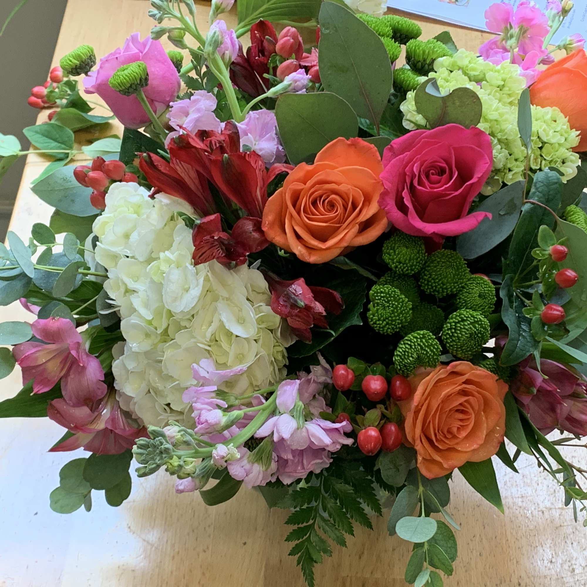 Mixed bouquet with orange and pink roses, hydrangea, and red blooms
