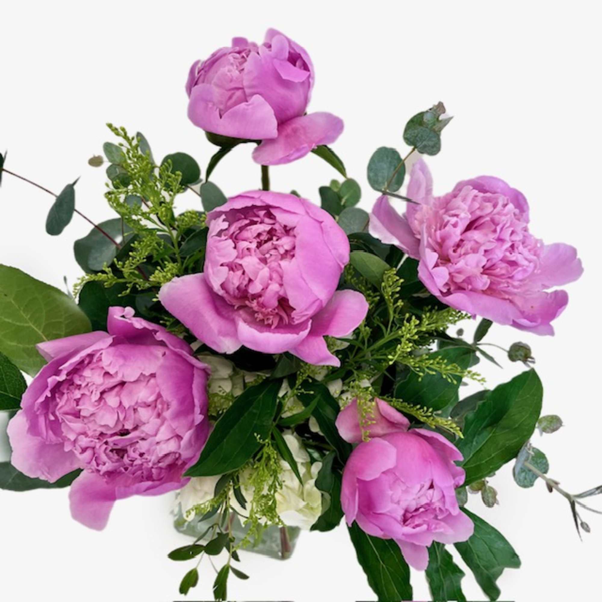 Pink peonies arranged with greenery in a clear vase