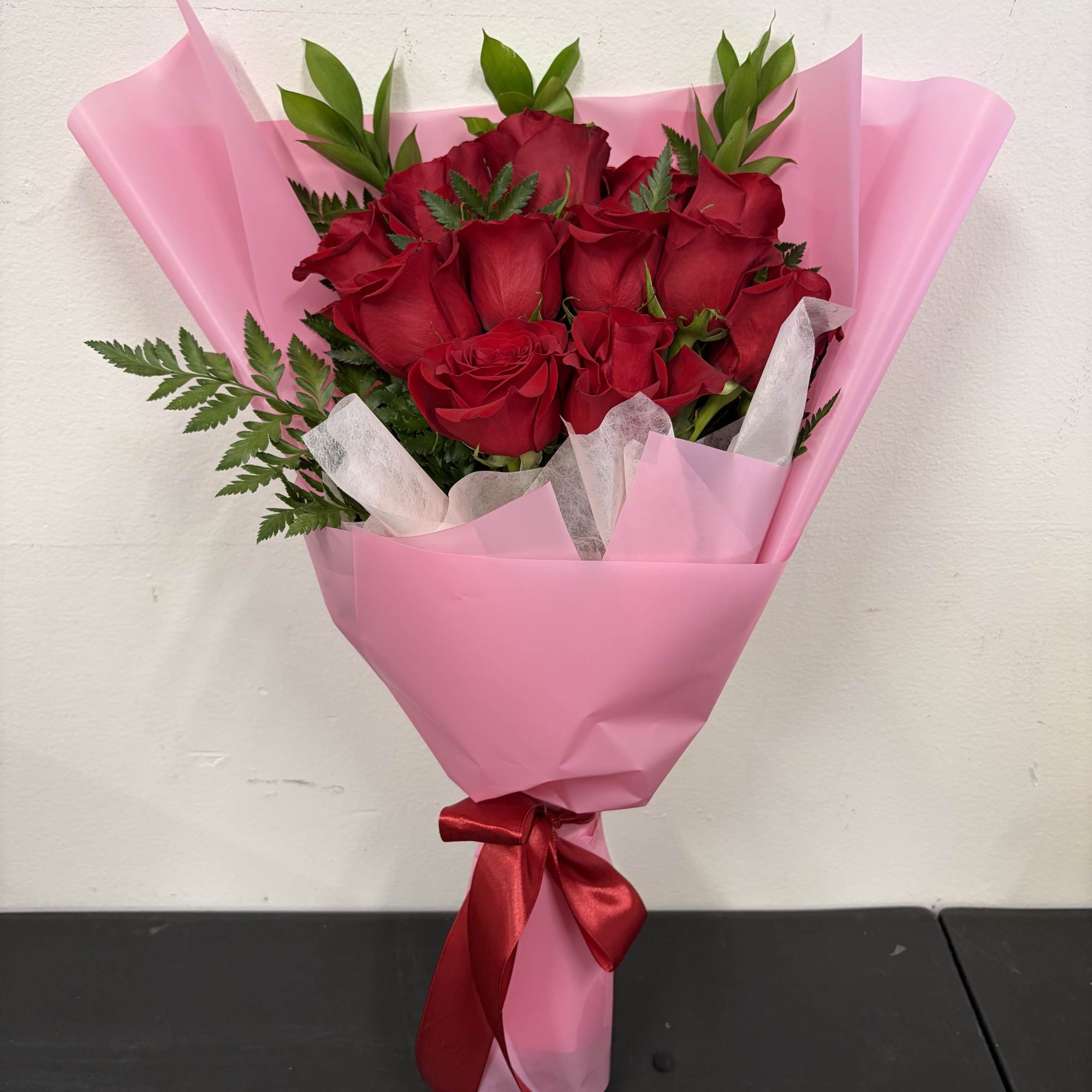 A classic bouquet of deep red roses wrapped in soft pink paper
