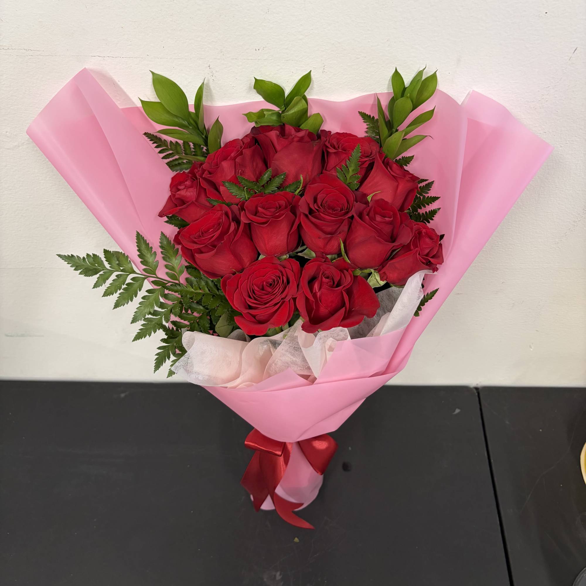 A classic bouquet of deep red roses wrapped in soft pink paper
