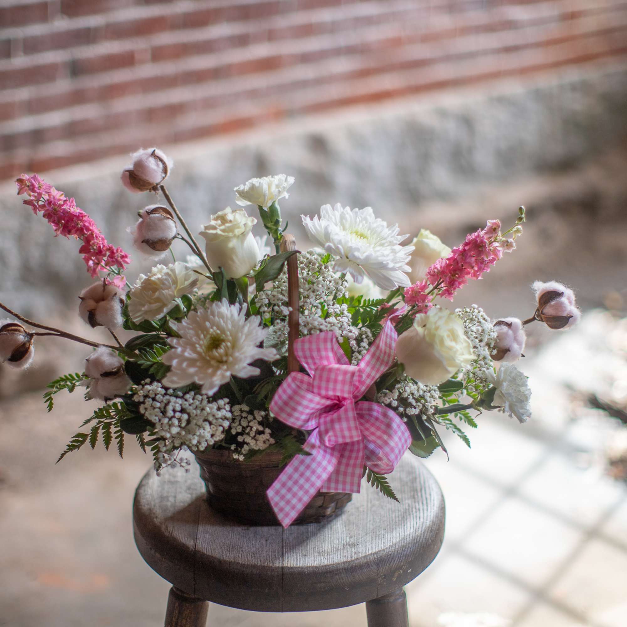 Basket arrangement of white and pink flowers with a gingham ribbon