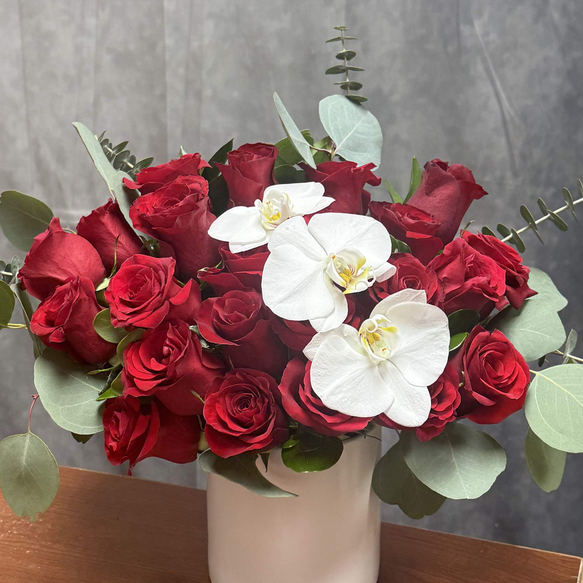 Classic red blooms embrace delicate white orchids, creating a breathtaking harmony of