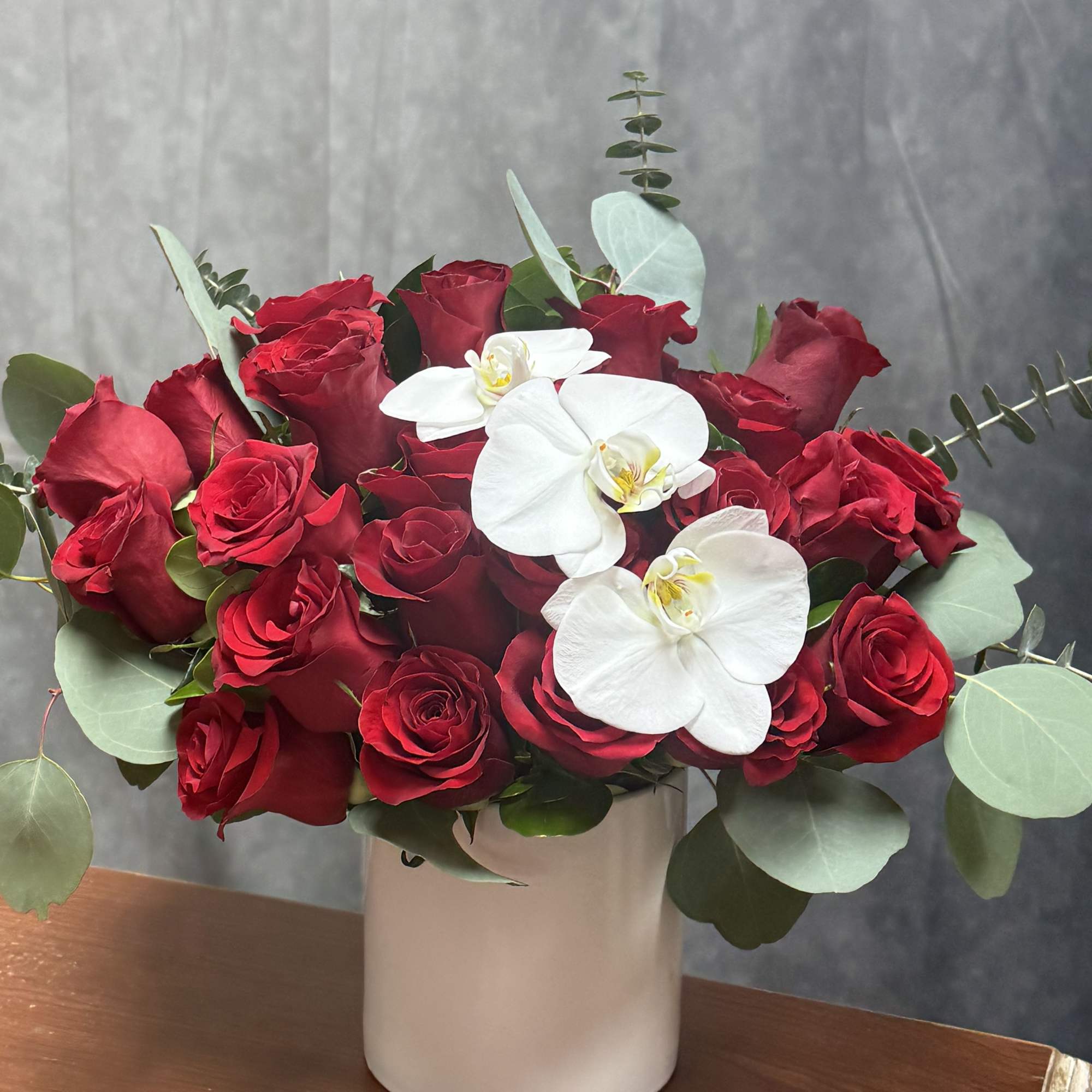 Classic red blooms embrace delicate white orchids, creating a breathtaking harmony of