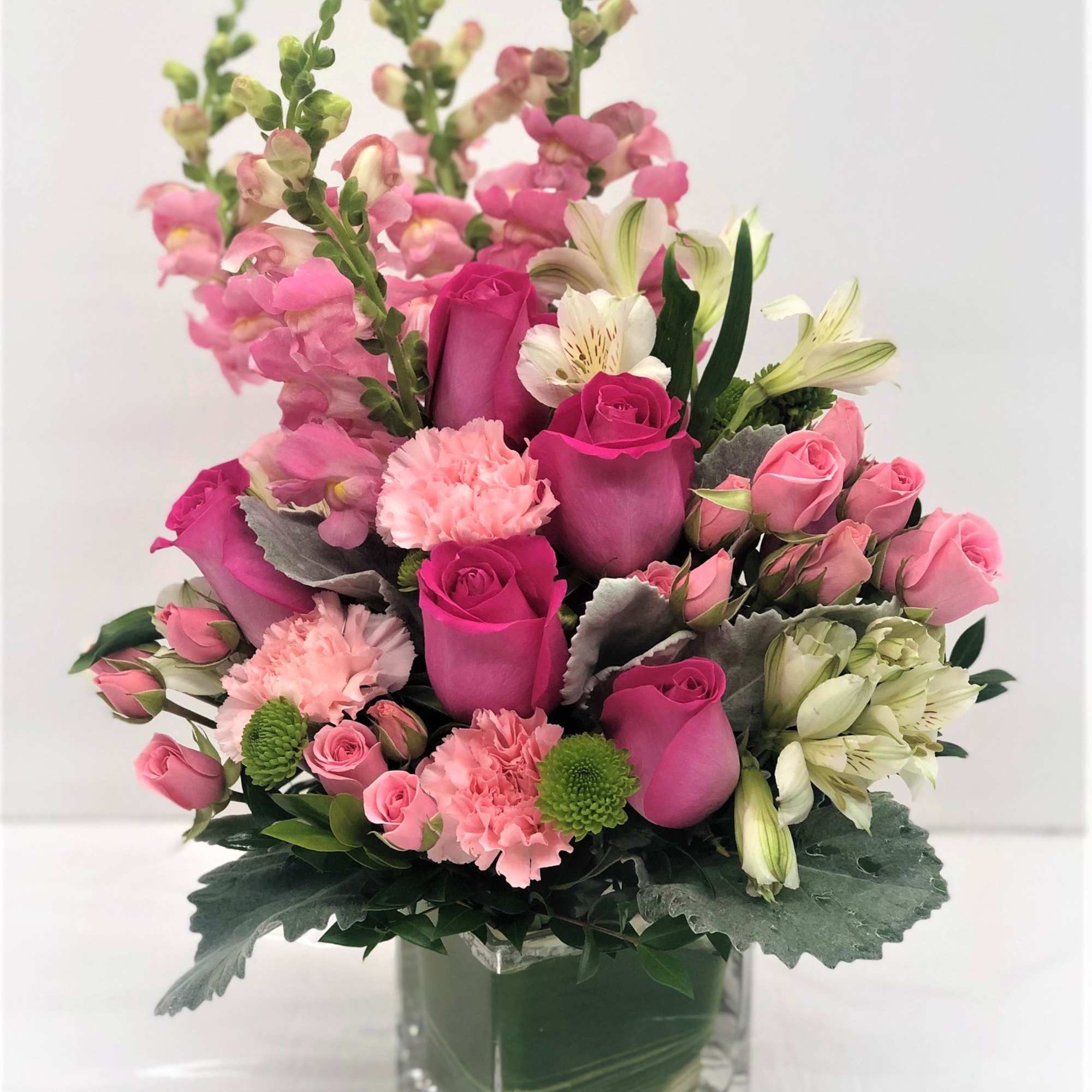 Pink roses and carnations in a clear square vase