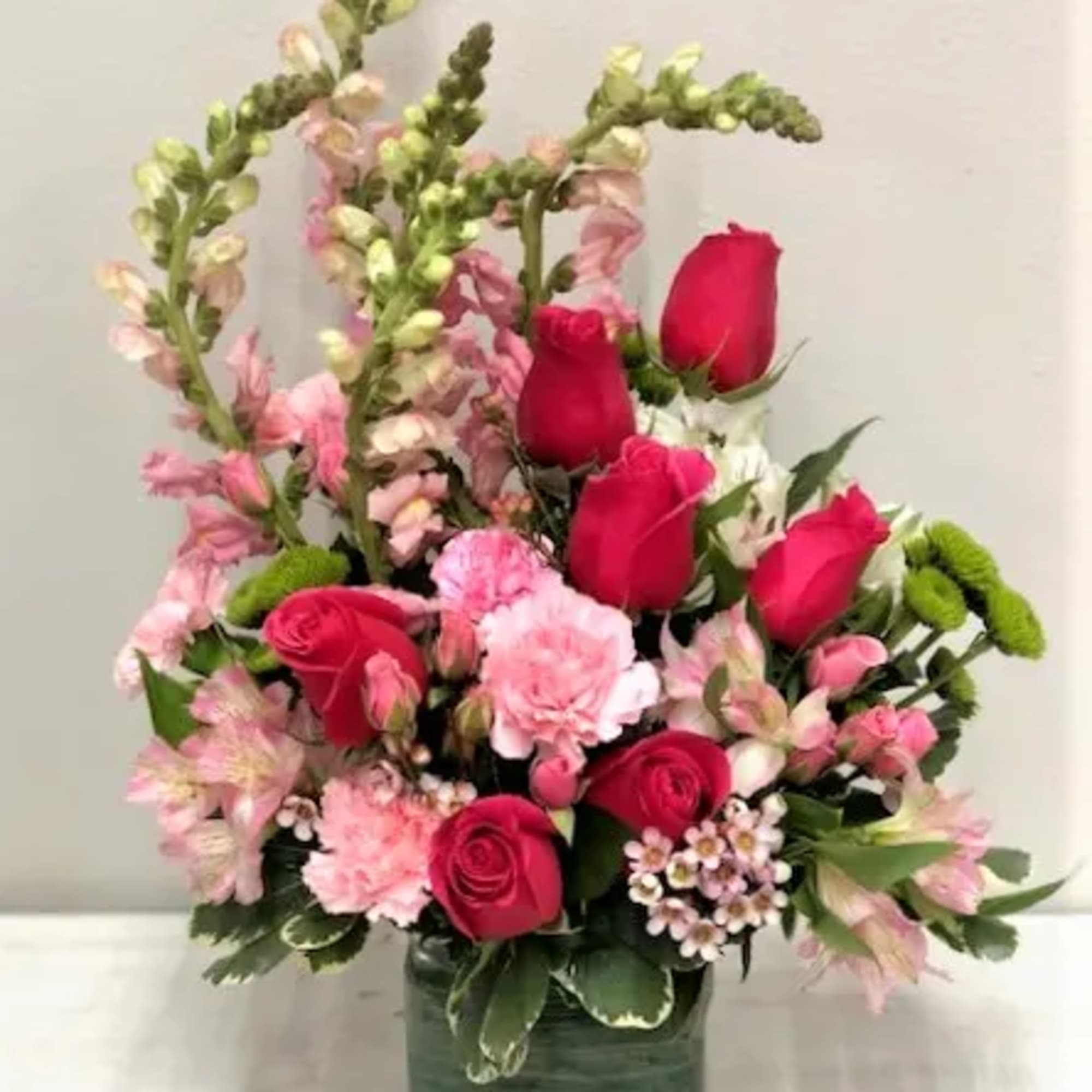Pink and red rose bouquet in a green square vase