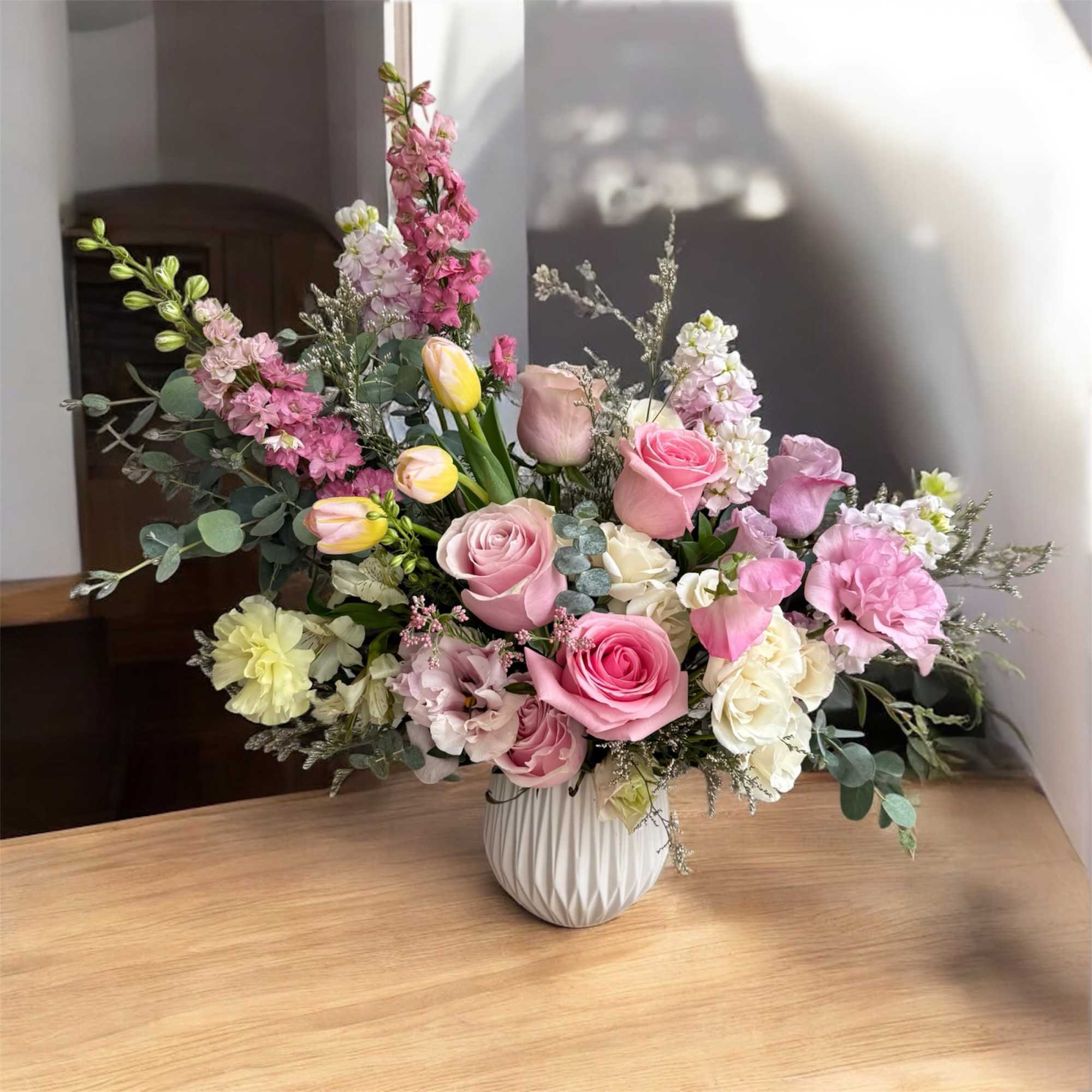 Pink and white mixed flower arrangement in a white vase