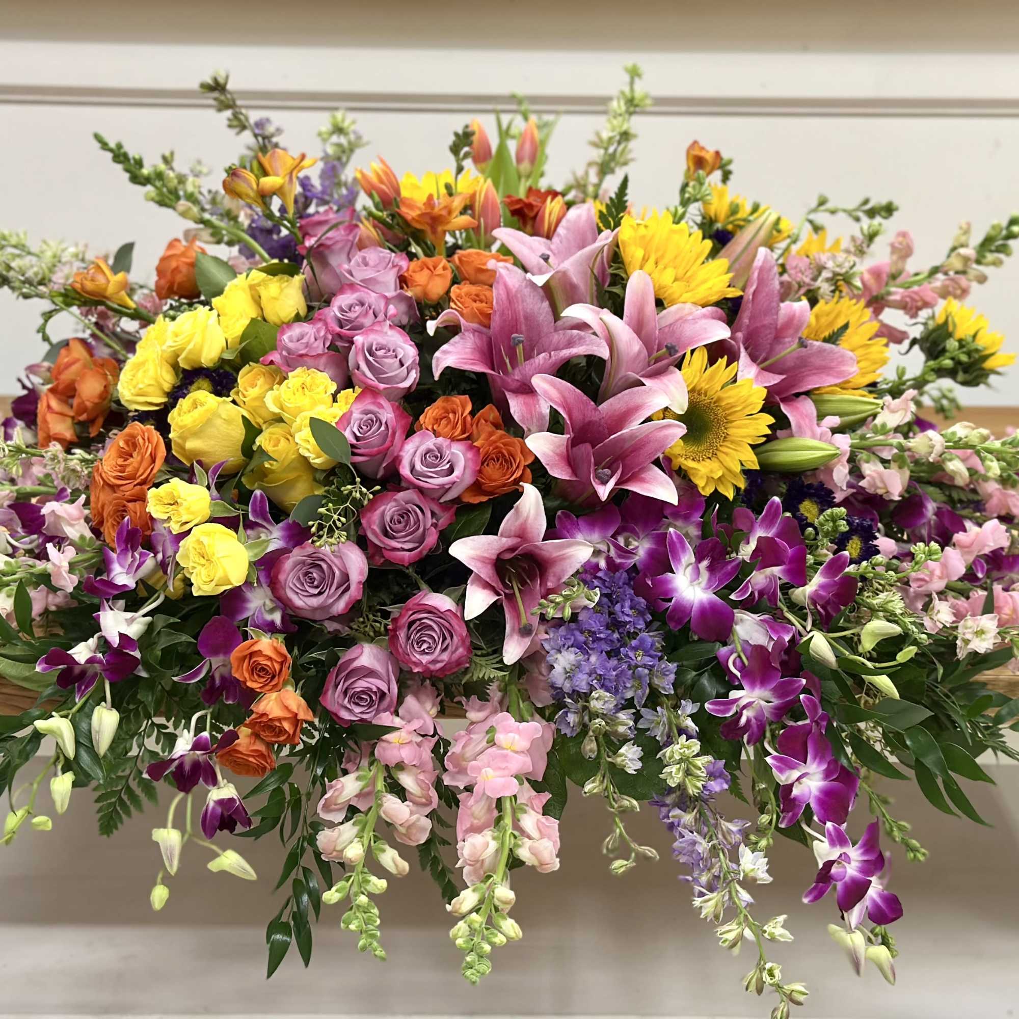 Large mixed bouquet with pink lilies, roses, orchids, and yellow sunflowers