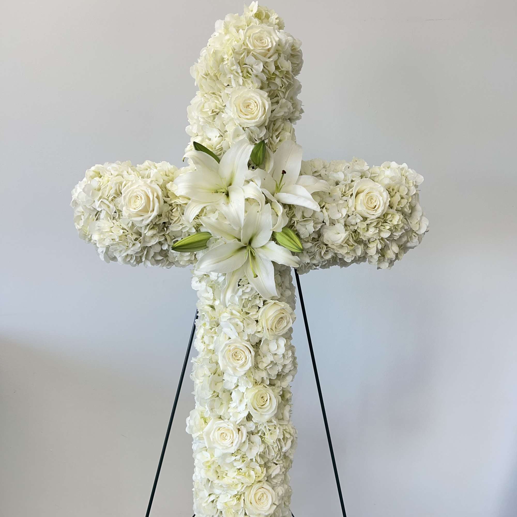 An all white tribute, this white cross funeral spray is pure and
