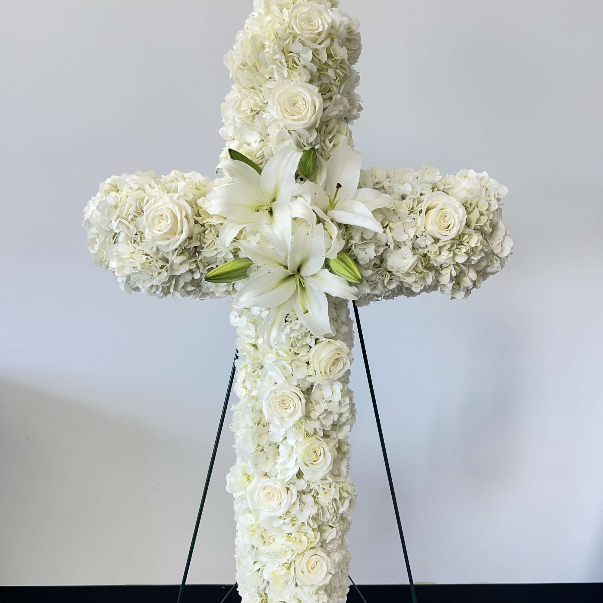 An all white tribute, this white cross funeral spray is pure and