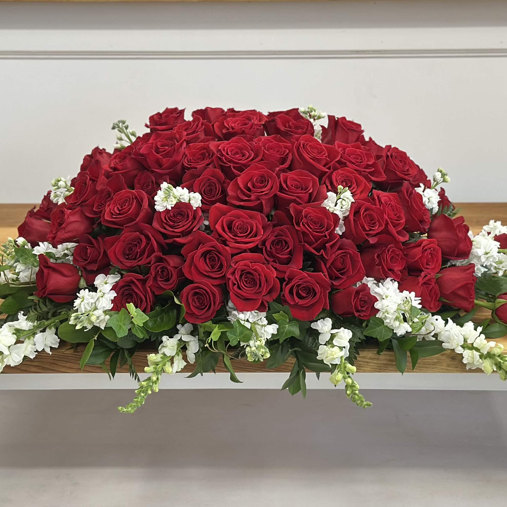 Large dome of red roses with white flowers on a wooden table