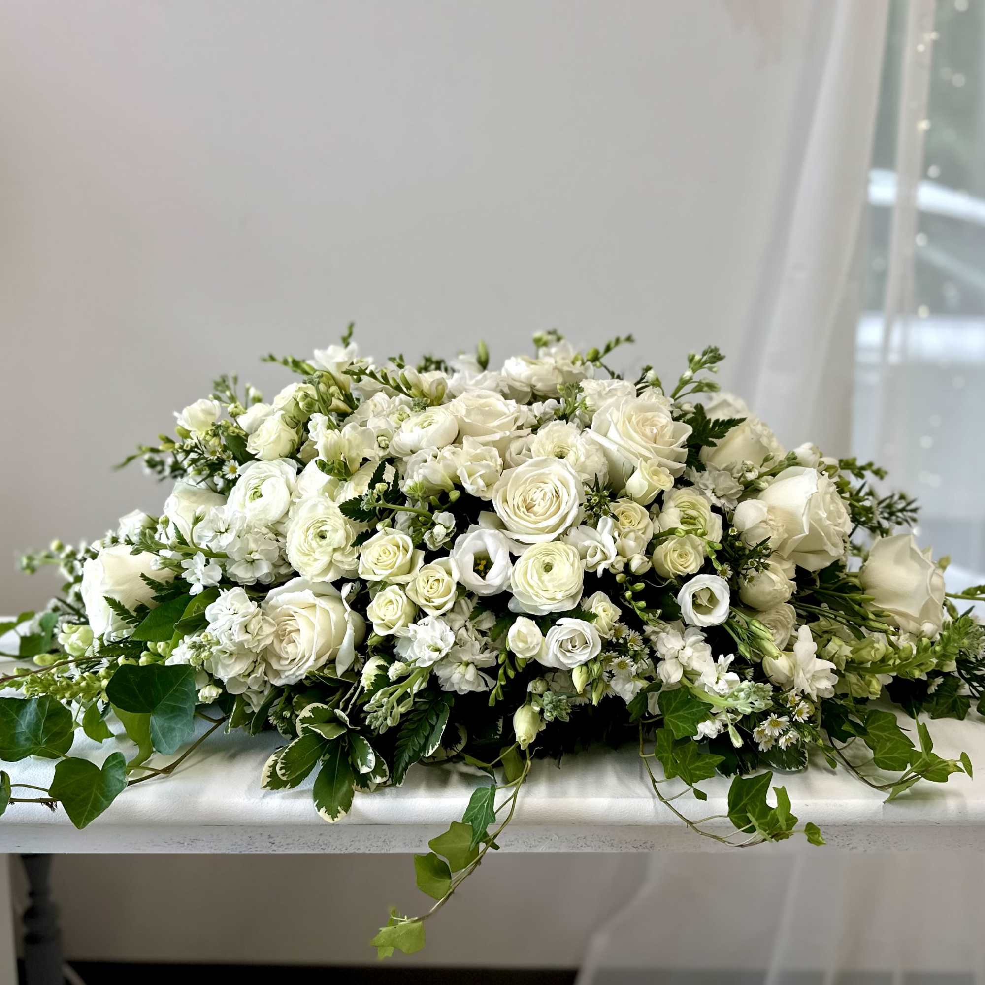 Low white floral centerpiece with roses and small blooms on a table
