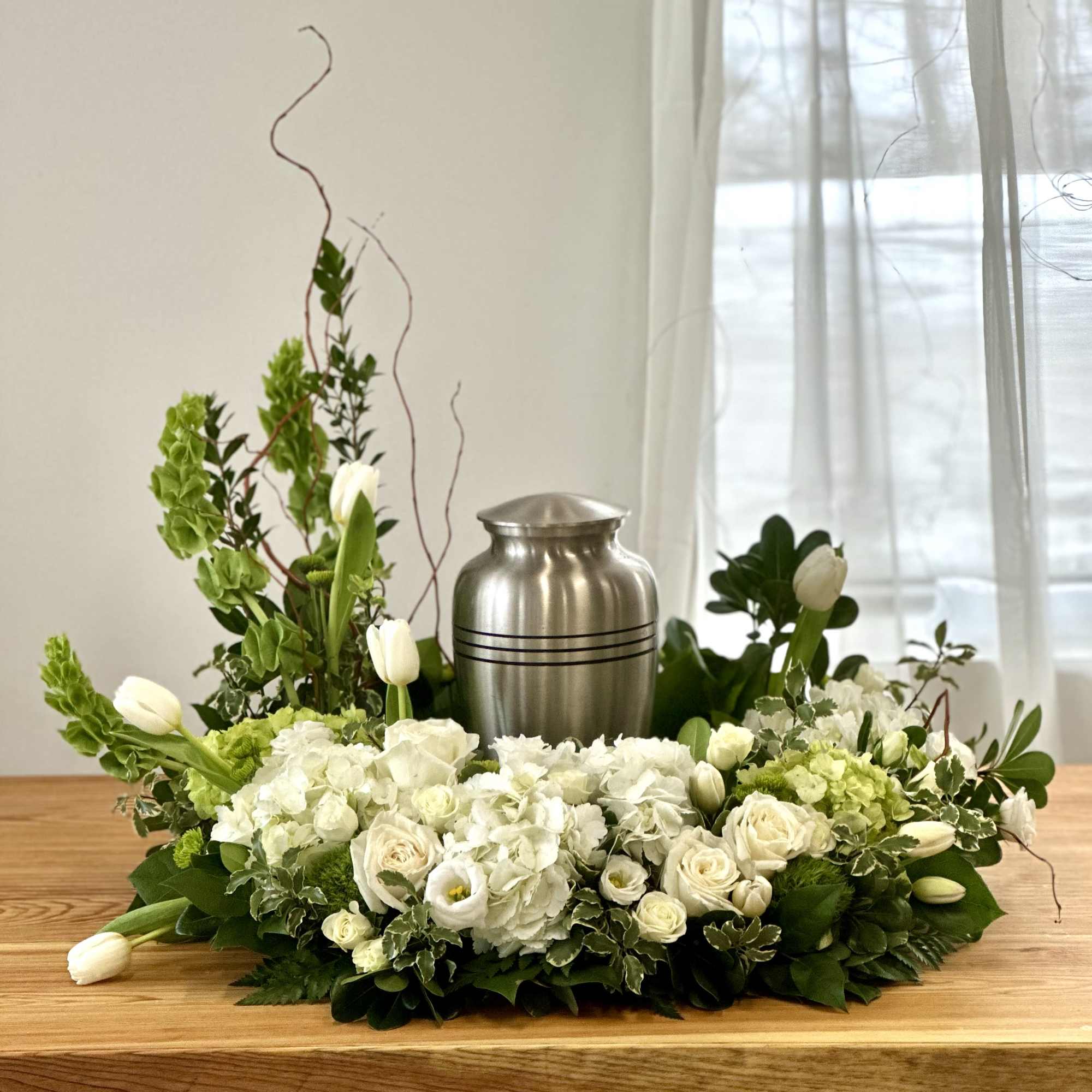 White floral centerpiece with tulips and roses around a silver urn