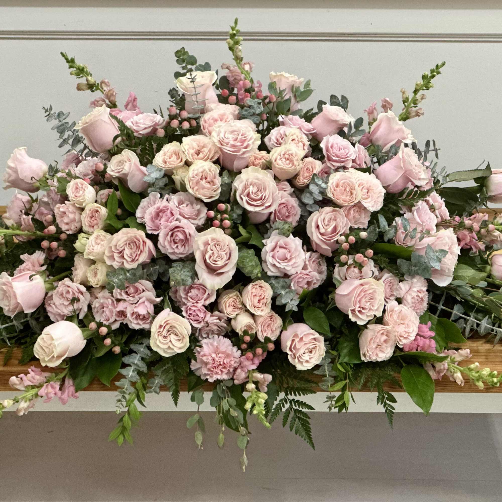 Large pink rose arrangement spread across a wooden table