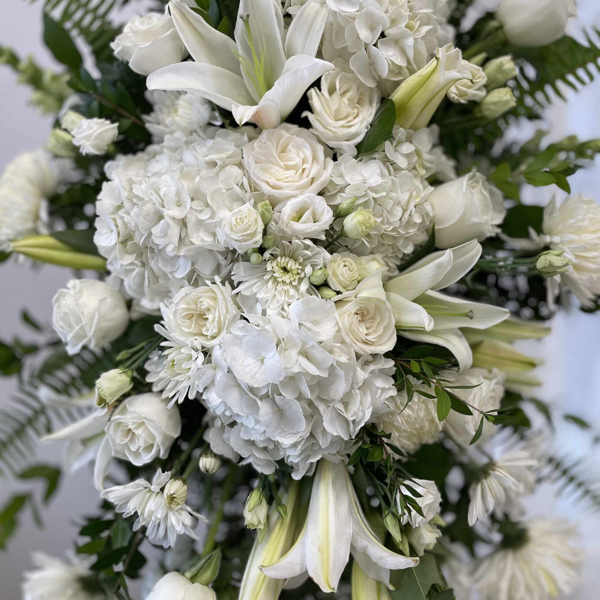White floral arrangement with lilies, roses, and hydrangeas