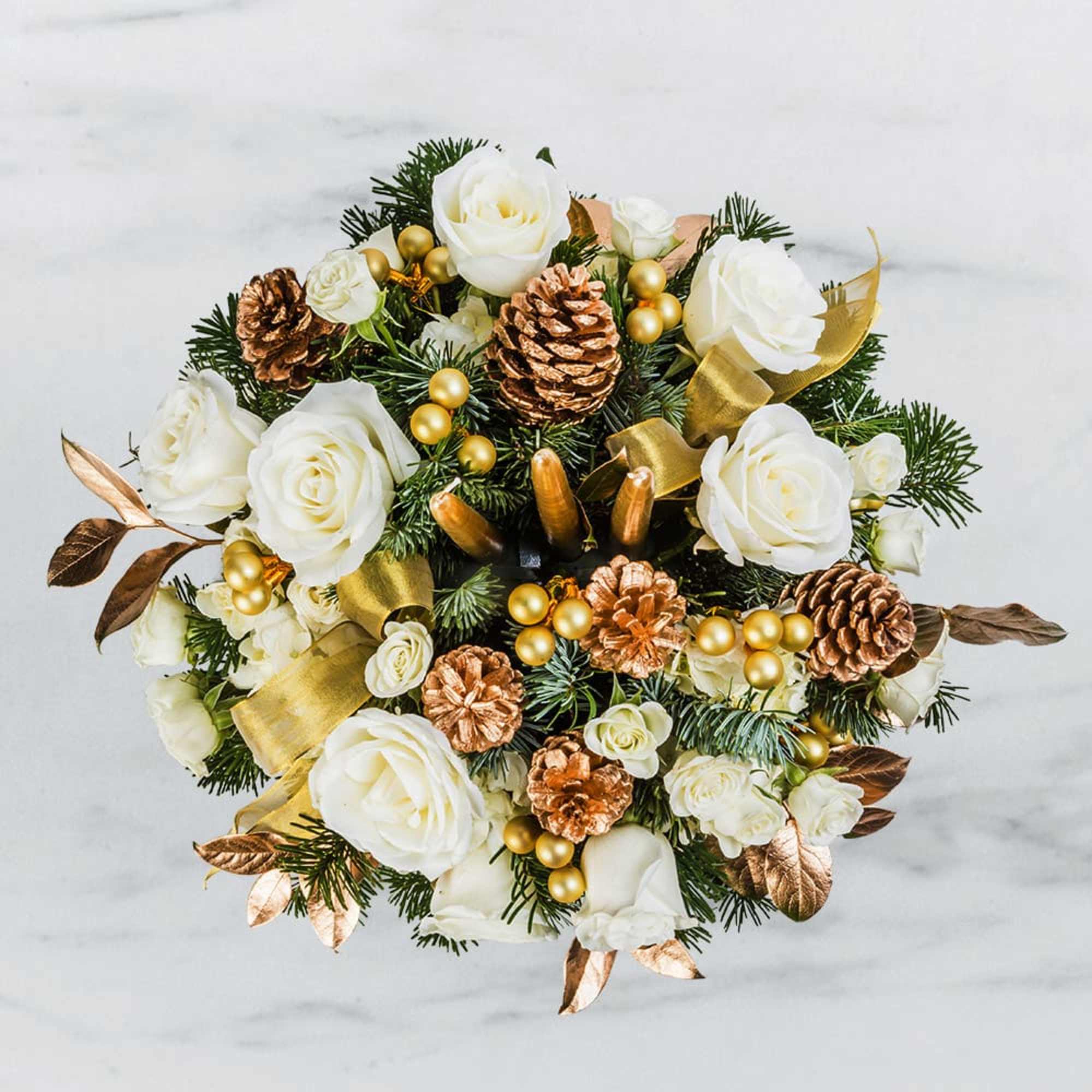 White roses with pinecones and gold ribbon in a holiday arrangement