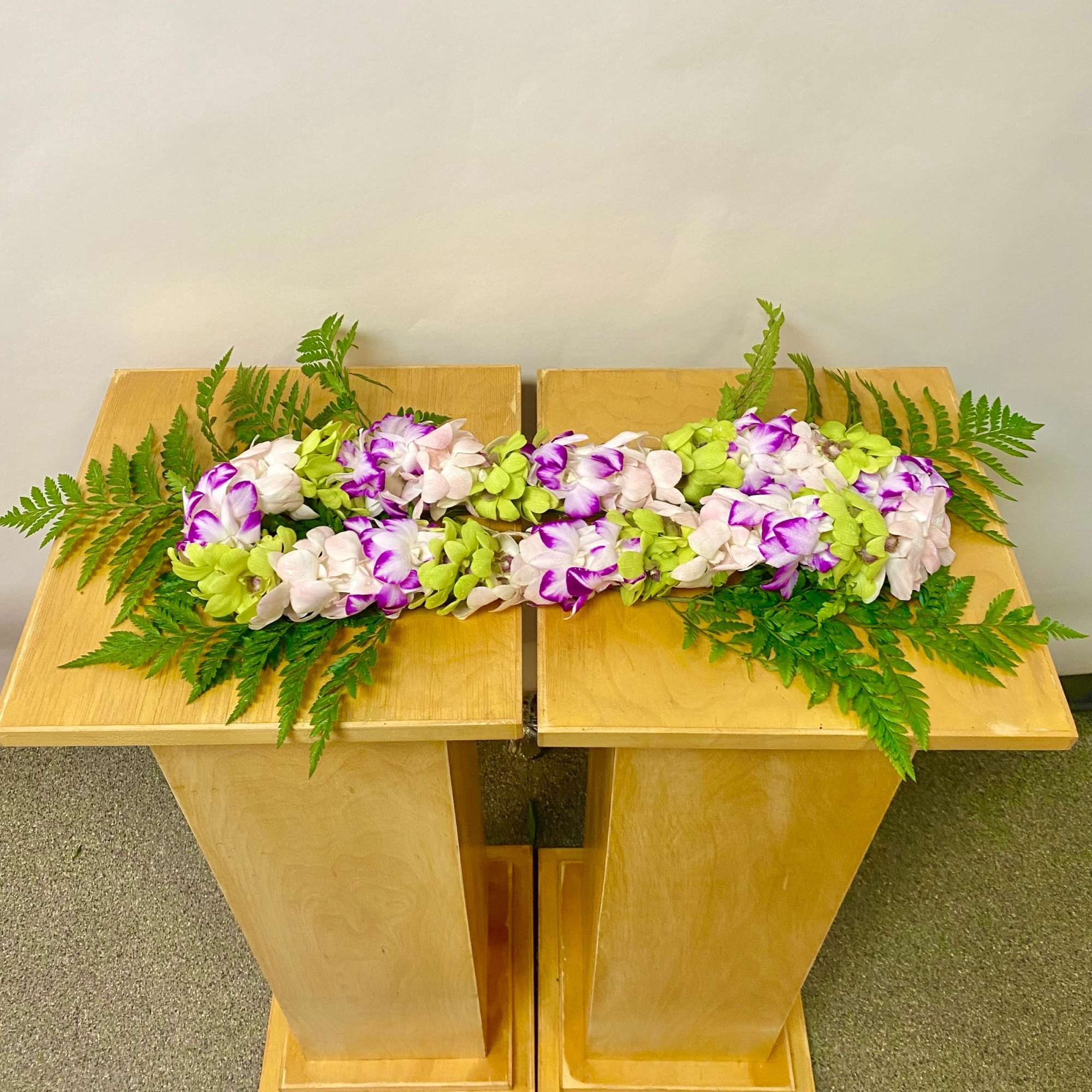 Long floral arrangement of white and purple orchids on a wooden stand