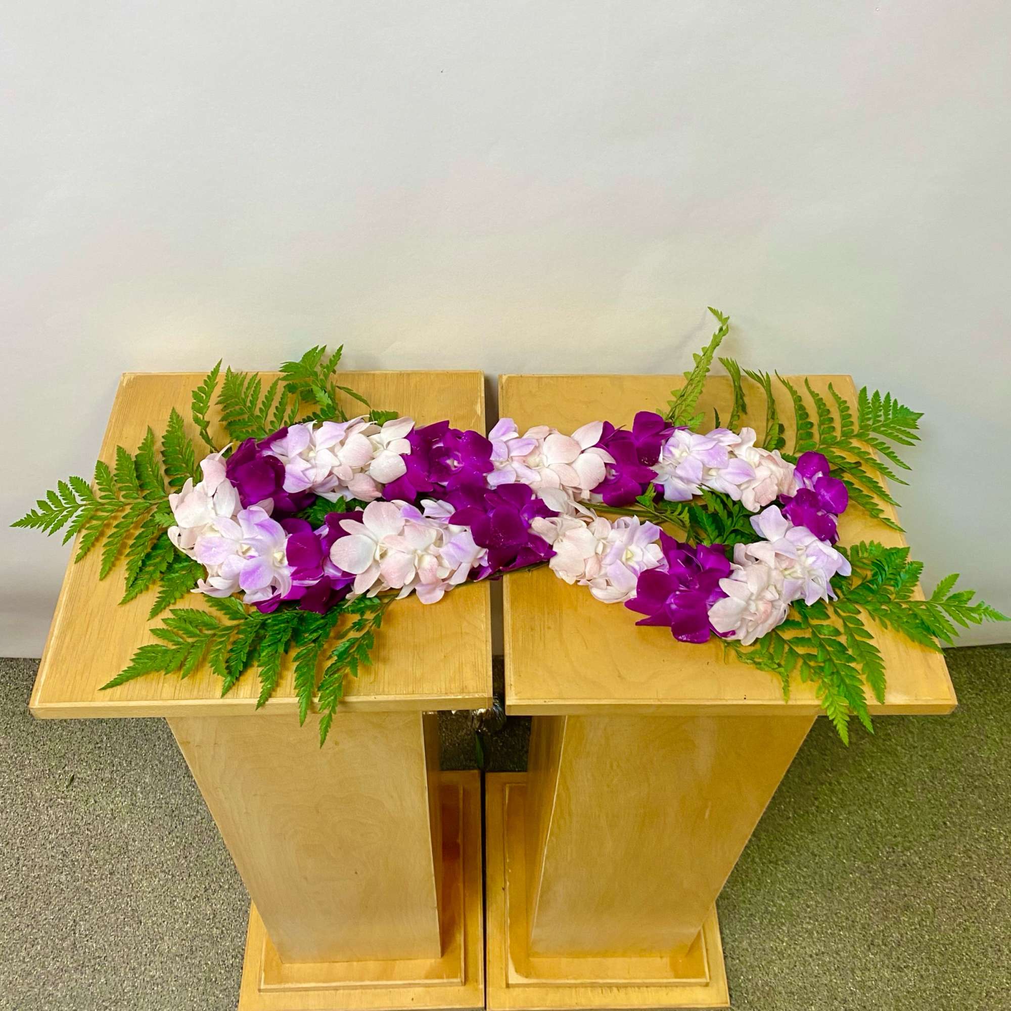 Purple and white orchid arrangement on a wooden stand