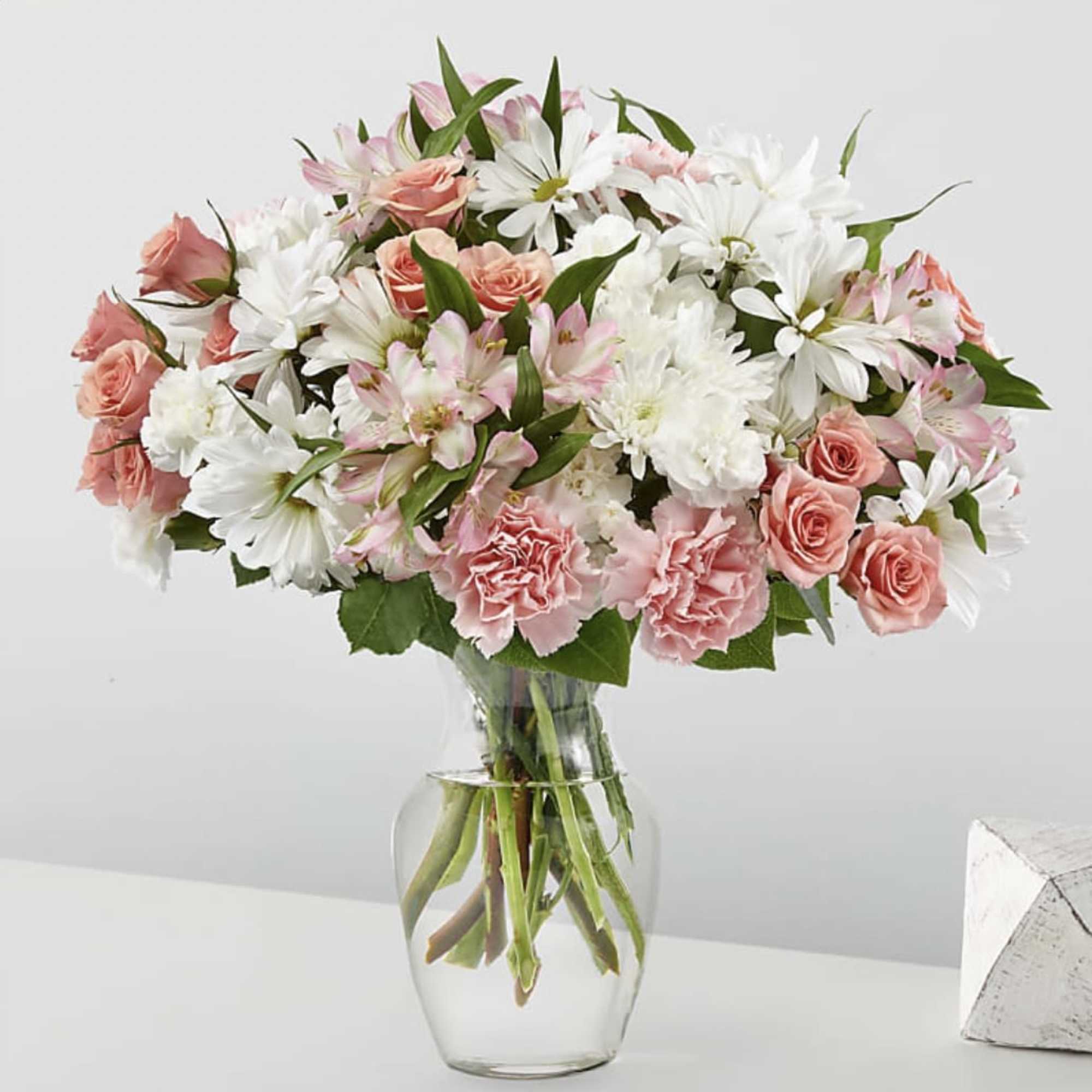 Pink roses and white daisies in a clear glass vase
