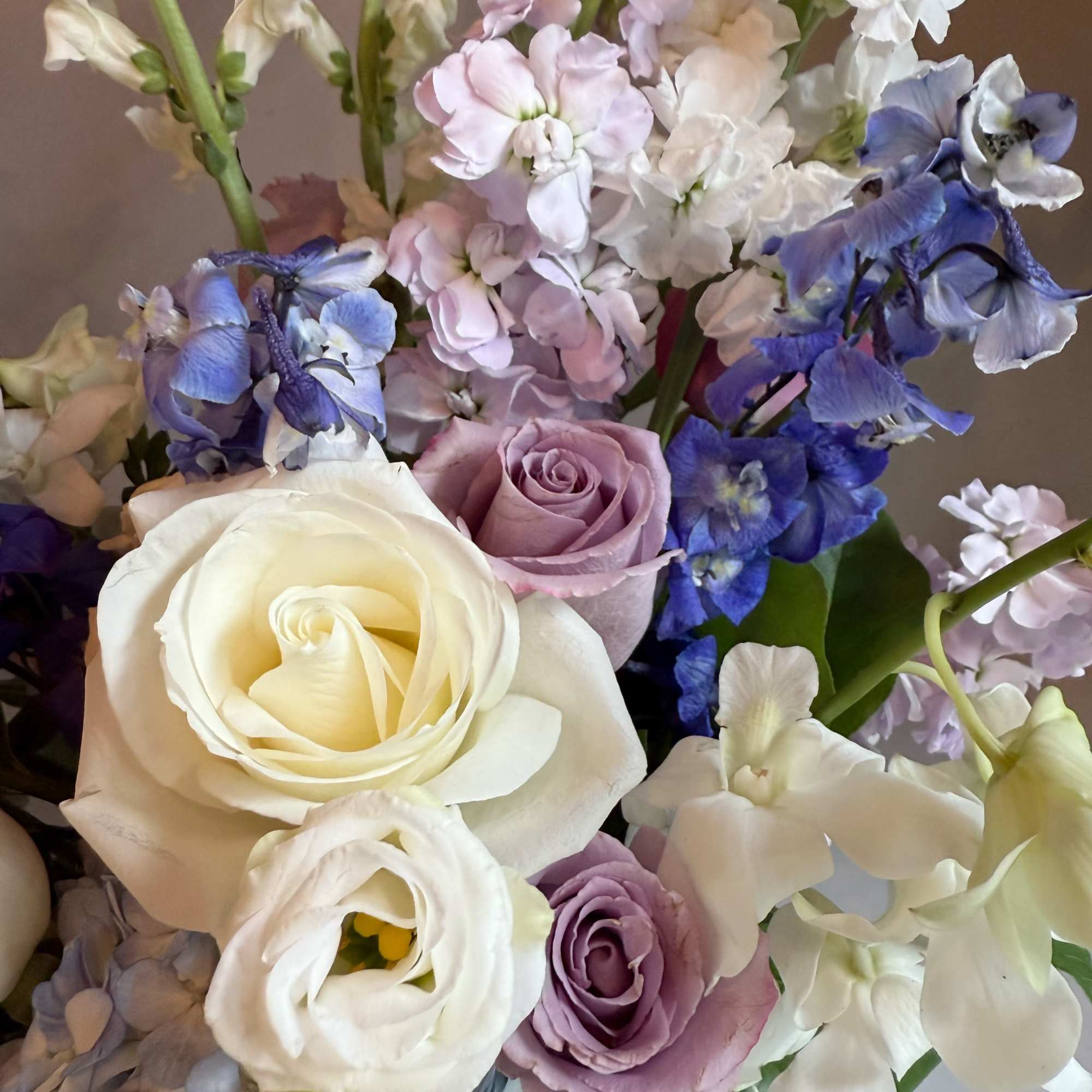Bouquet of white, lavender, and blue flowers with roses and tall blooms