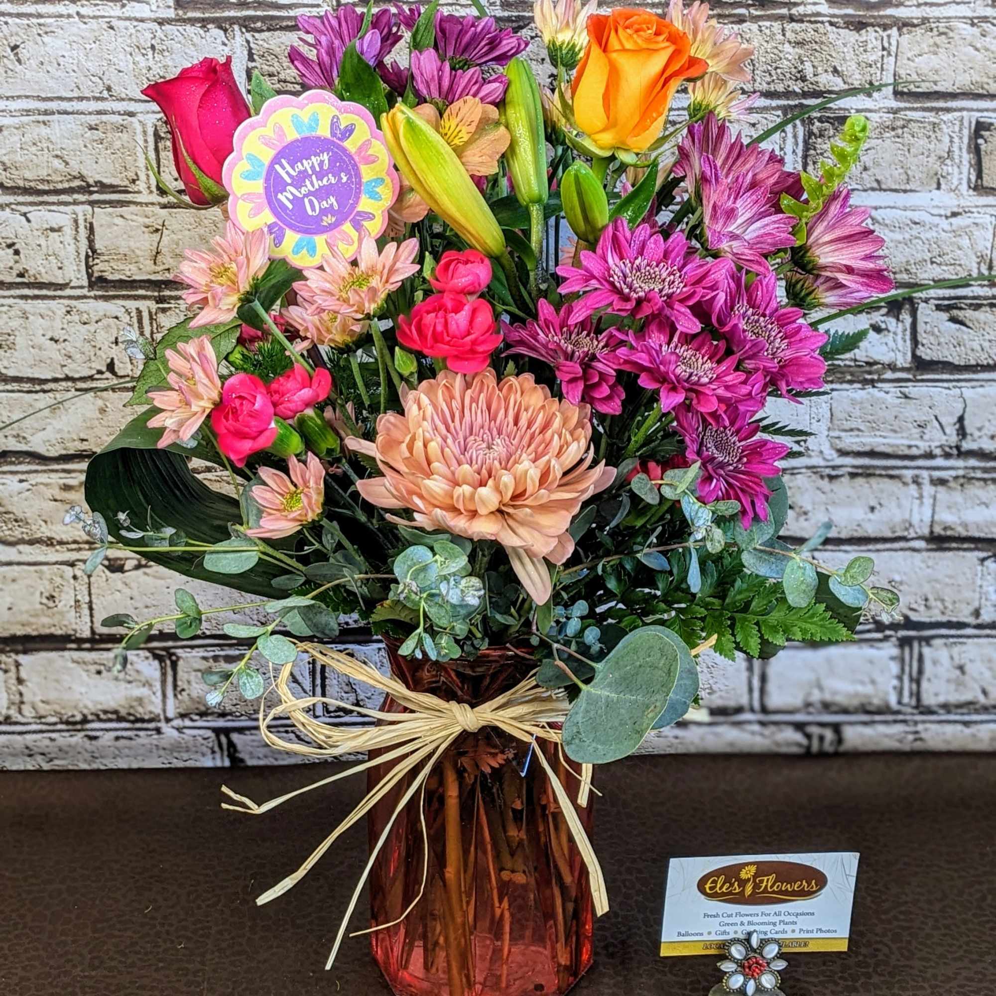Mixed bouquet in a pink glass vase with roses and chrysanthemums