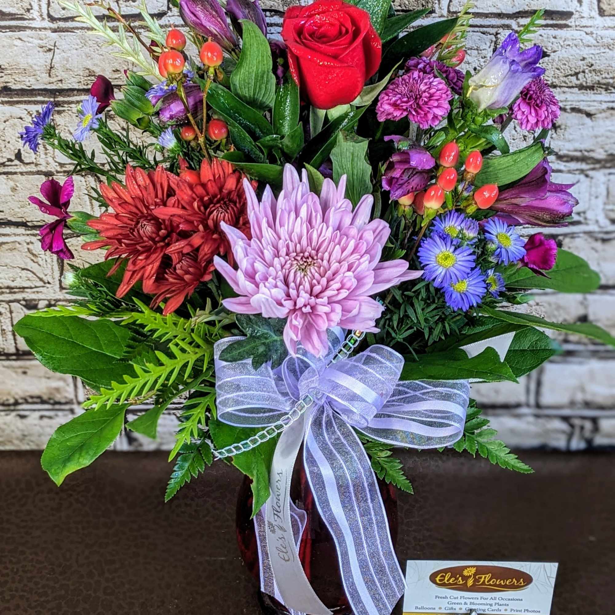 Mixed bouquet with a red rose, purple and pink blooms in a vase