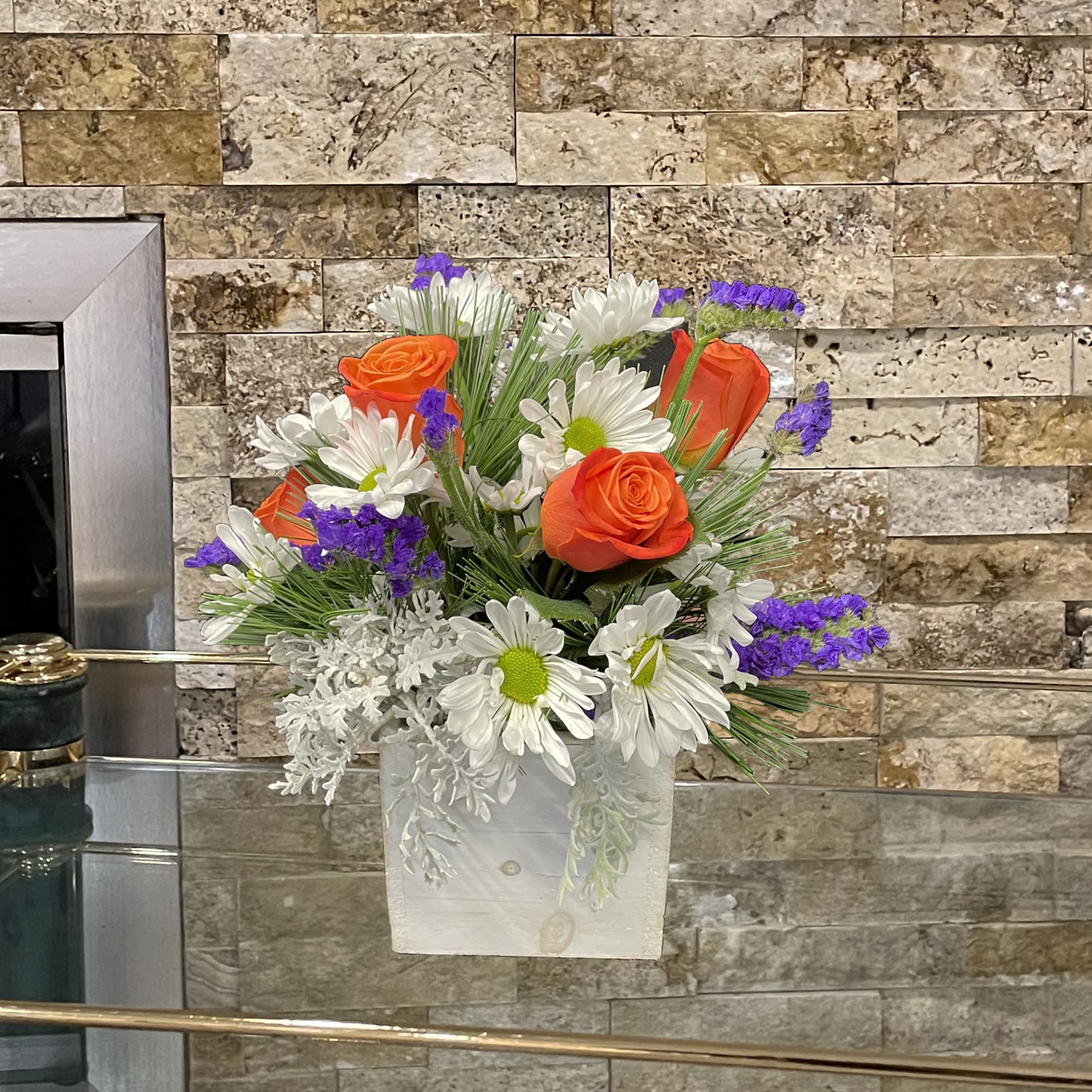 Orange roses and white daisies in a white square vase