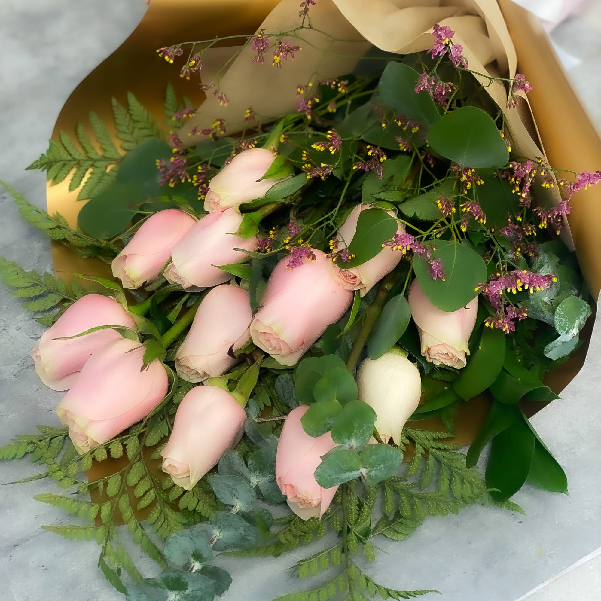 Bouquet of pale pink roses with greenery and gold wrapping