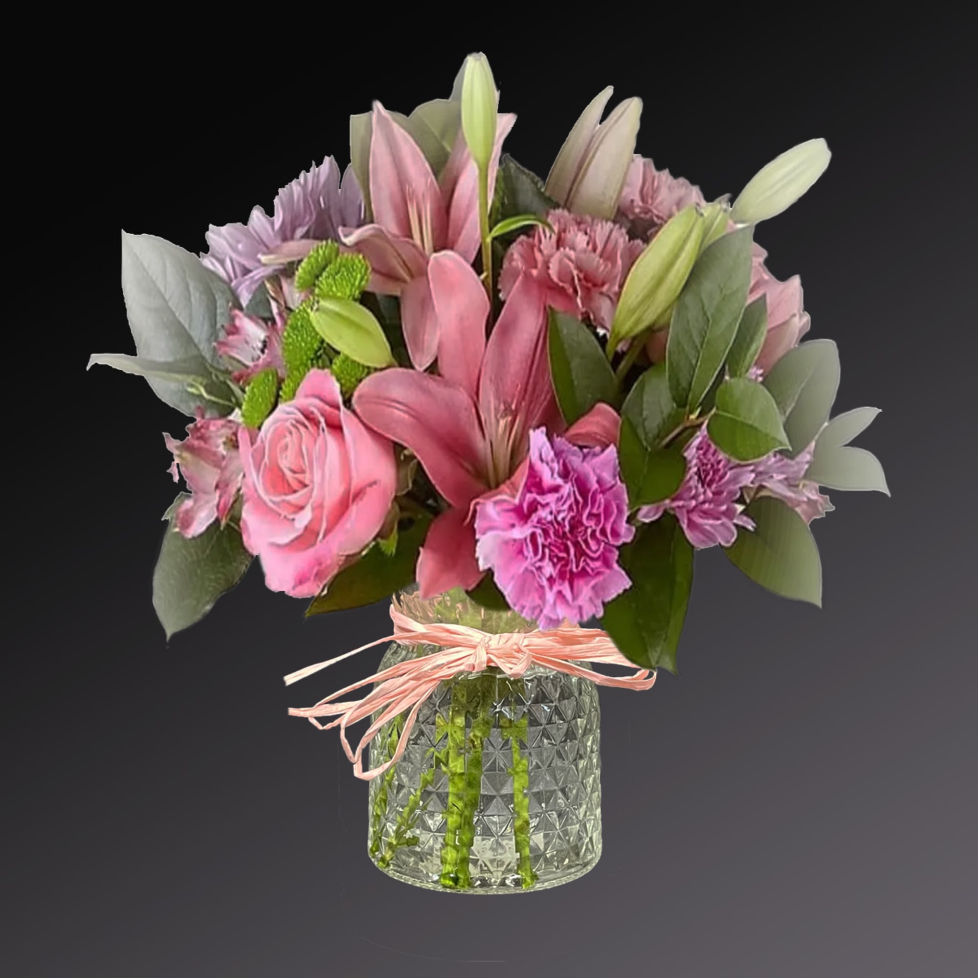 Pink and purple bouquet in a glass vase with a ribbon tie