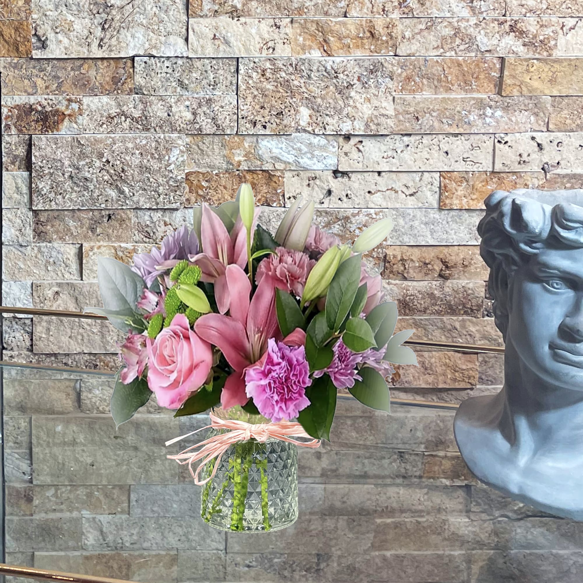Pink and purple bouquet in a glass vase with a ribbon