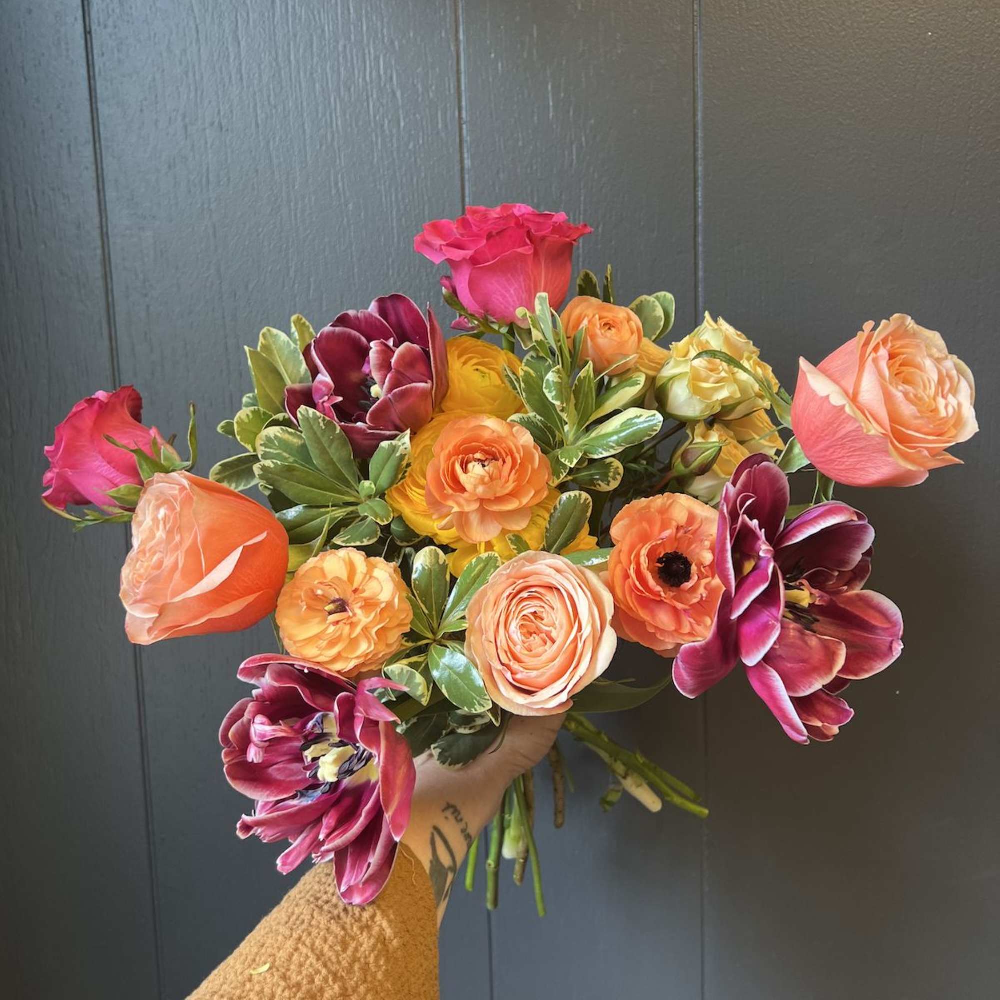 Handheld bouquet of pink, orange, and purple flowers