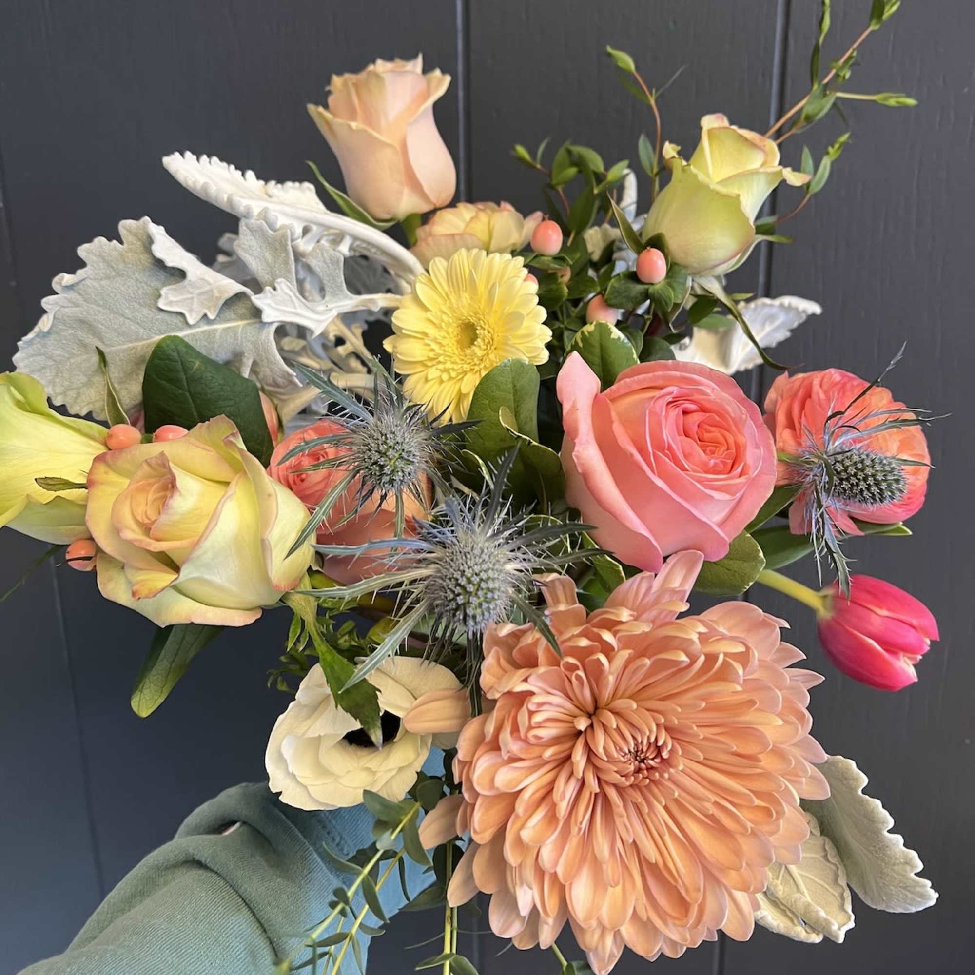 Handheld bouquet with pink and peach roses, a peach chrysanthemum, and yellow blooms