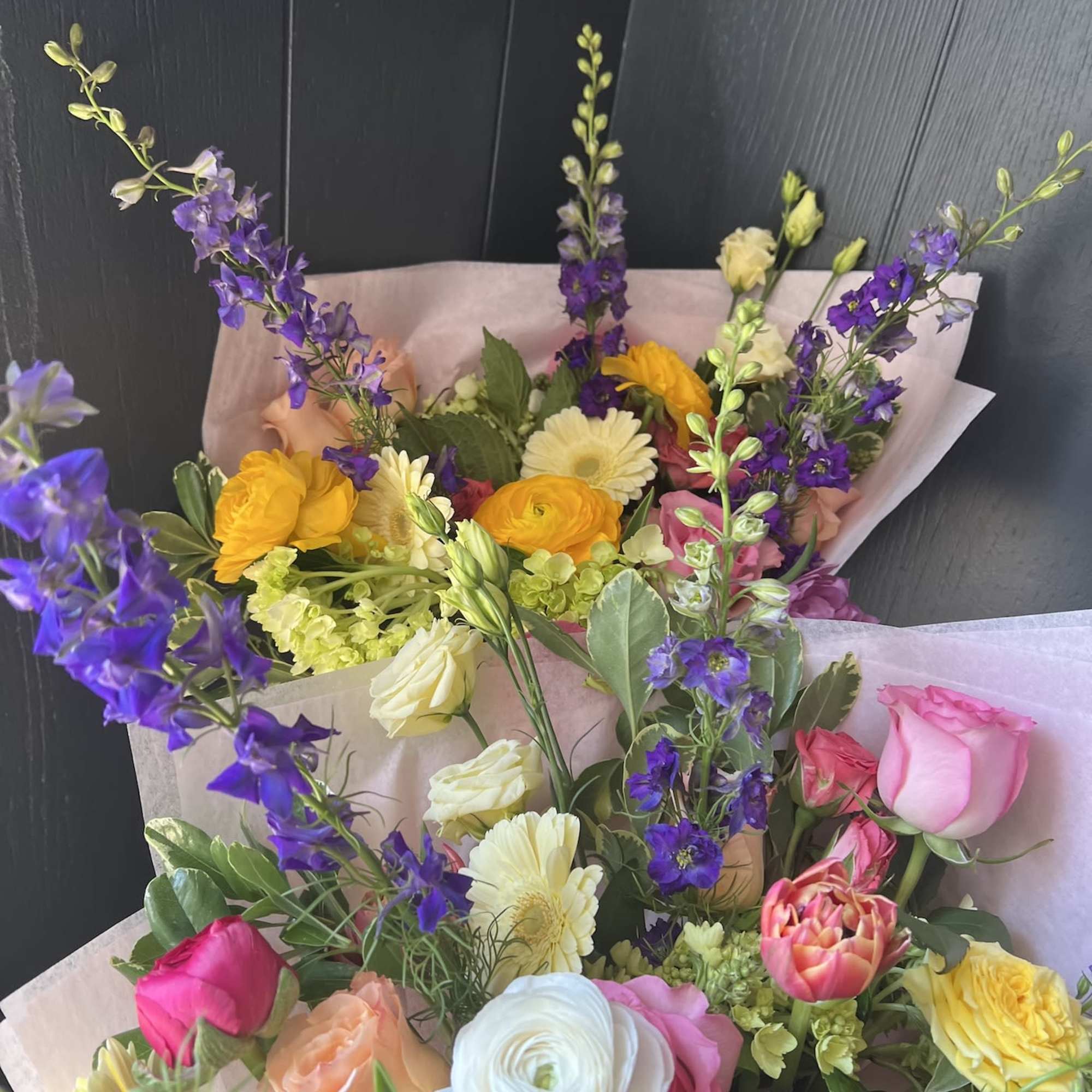 Seasonal, colorful flowers and foliage artfully arranged, wrapped in tissue and ready