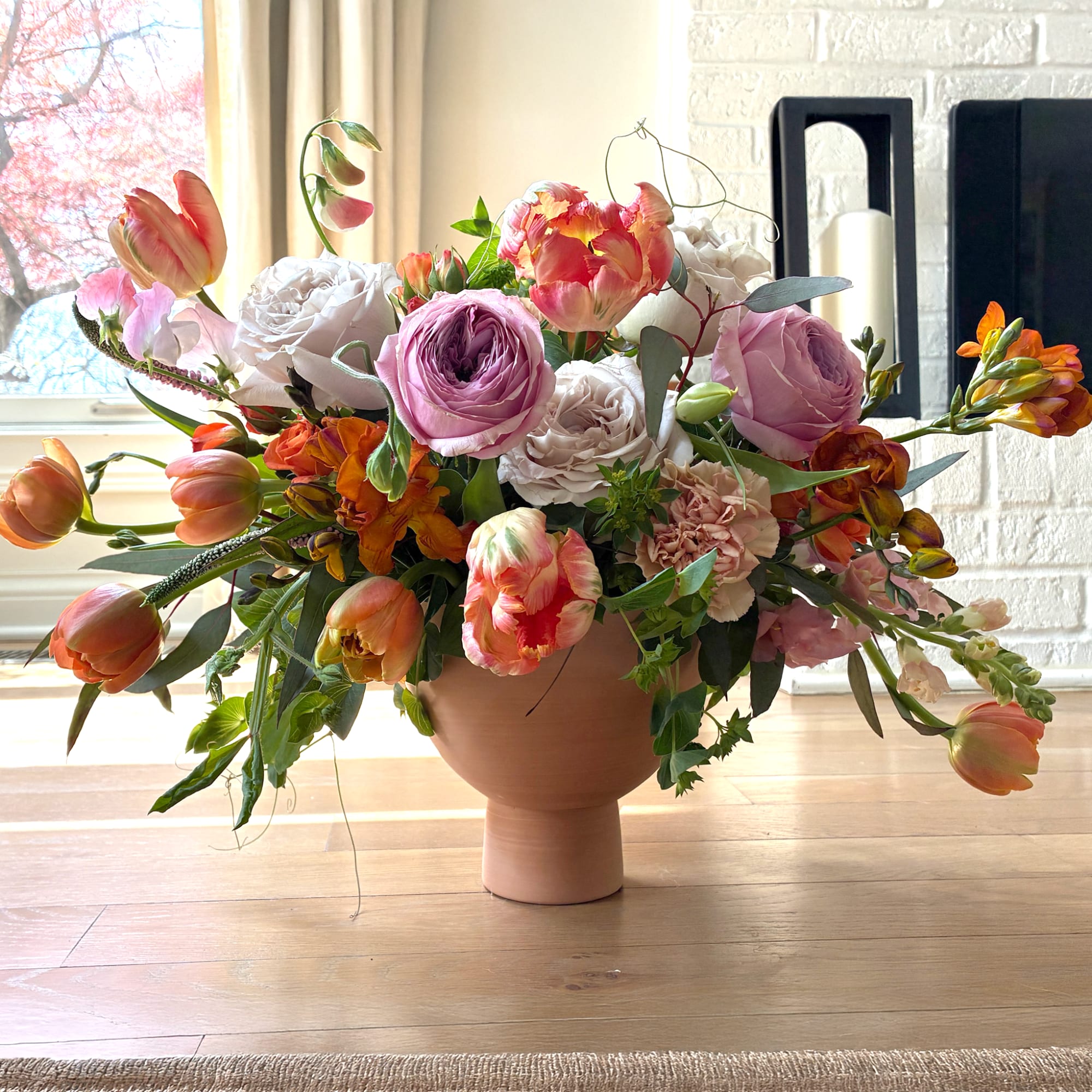 Large mixed bouquet of pink, orange, and white flowers in a terracotta vase