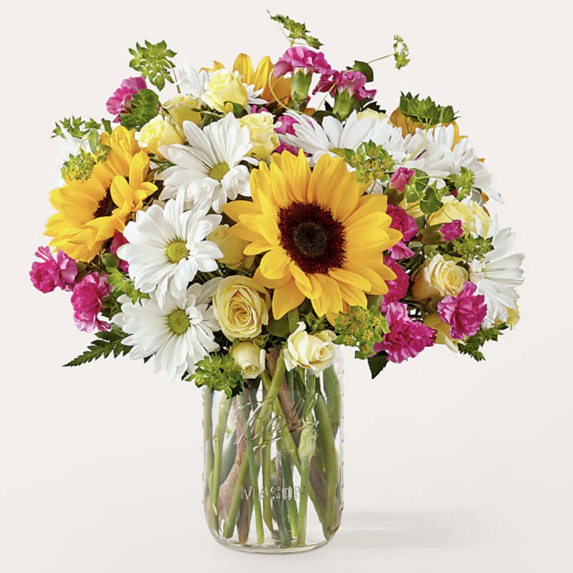 Bouquet of sunflowers, white daisies, and pink flowers in a glass vase