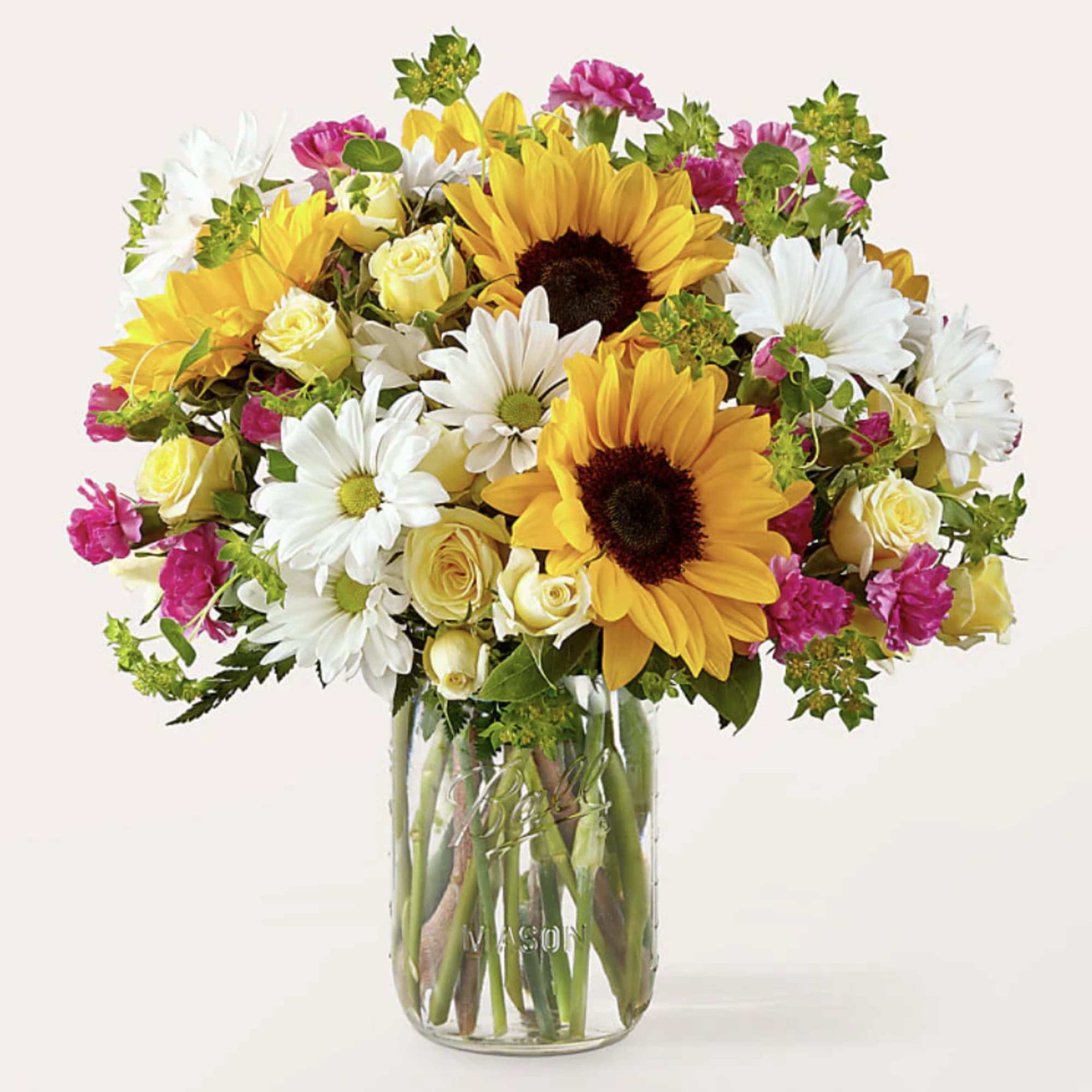 Bouquet of sunflowers, white daisies, and yellow roses in a glass mason jar
