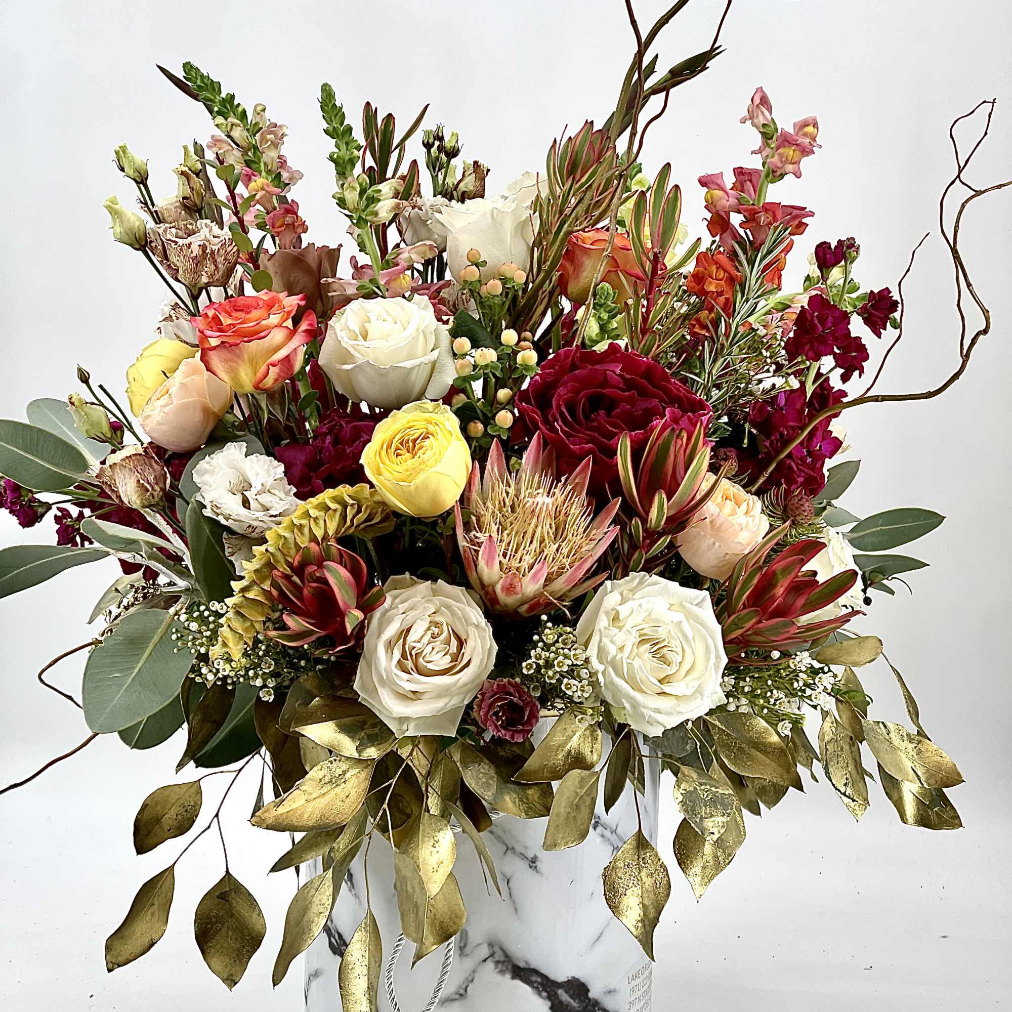 Mixed bouquet of roses and other blooms in a marble-patterned box