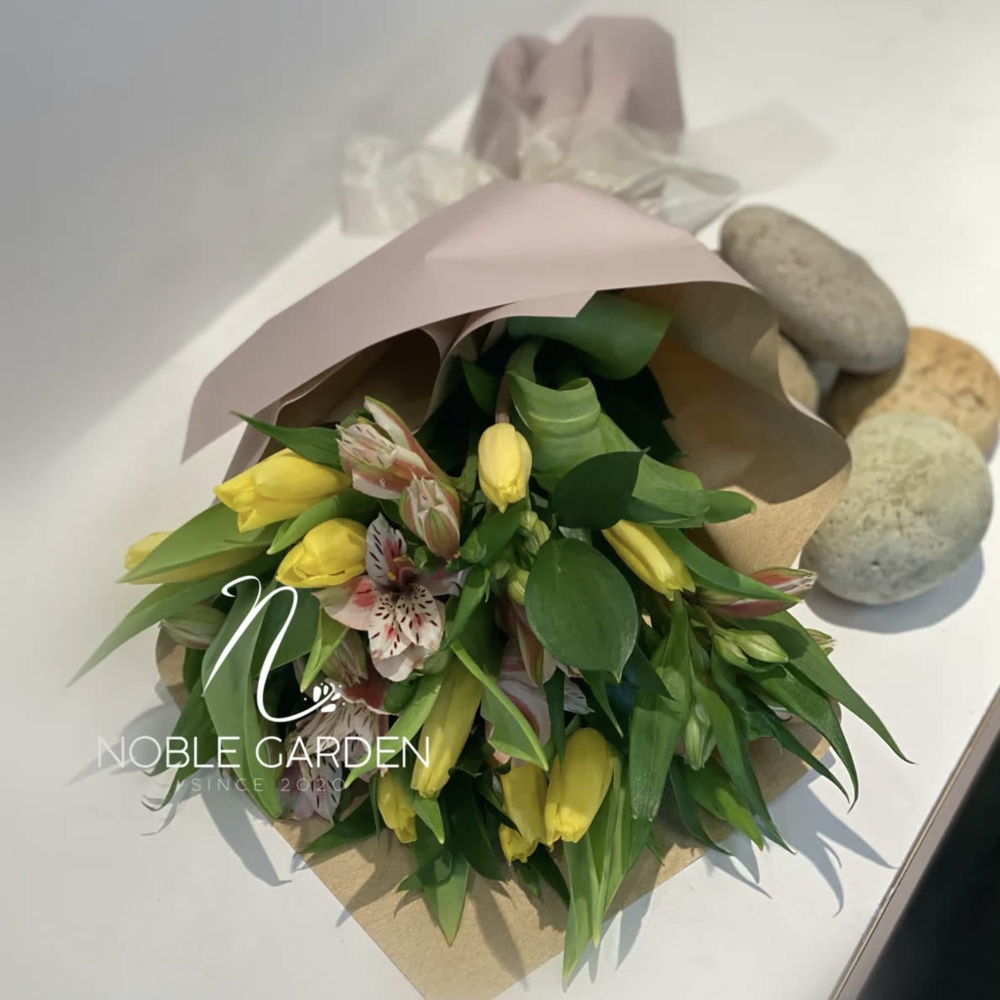 Bouquet of yellow tulips and pink alstroemeria wrapped in paper