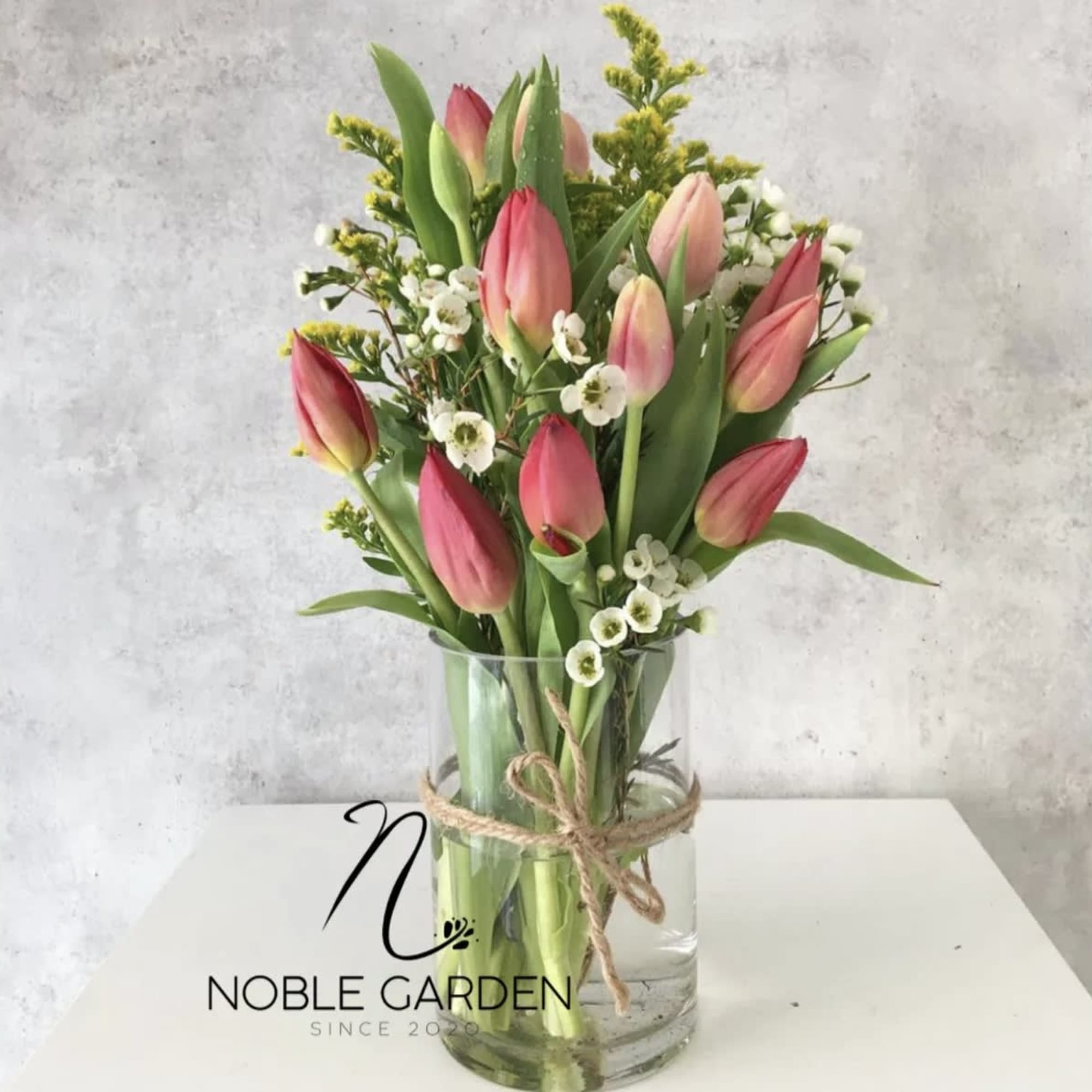 Pink tulips arranged in a clear glass vase with small white filler flowers