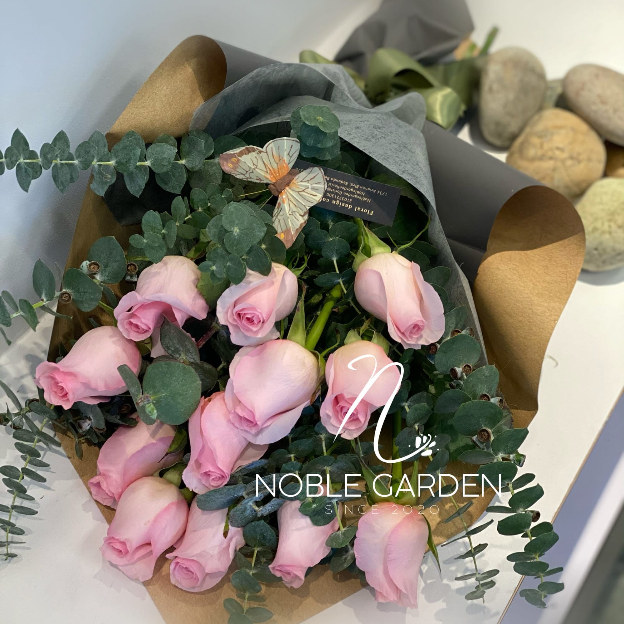 Bouquet of pale pink roses wrapped in dark paper with eucalyptus
