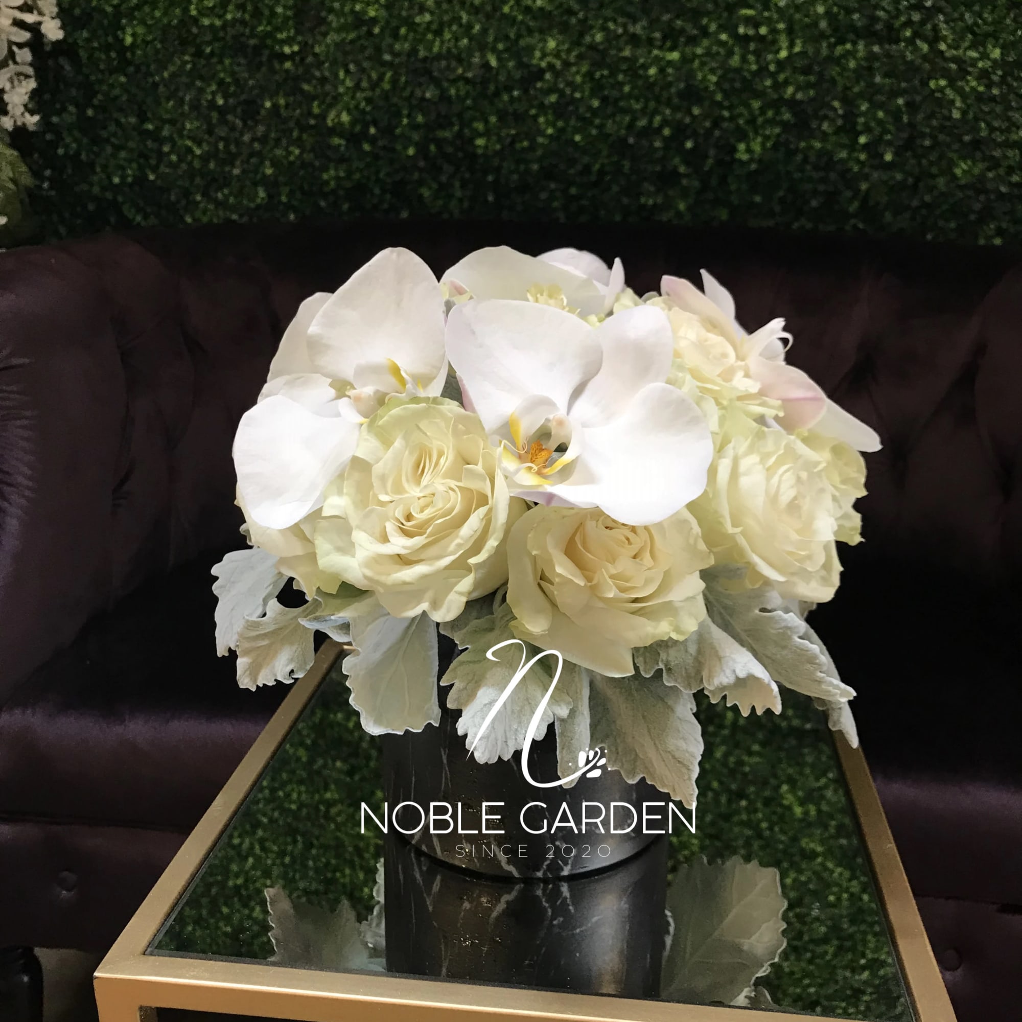 White roses and orchids arranged in a black vase