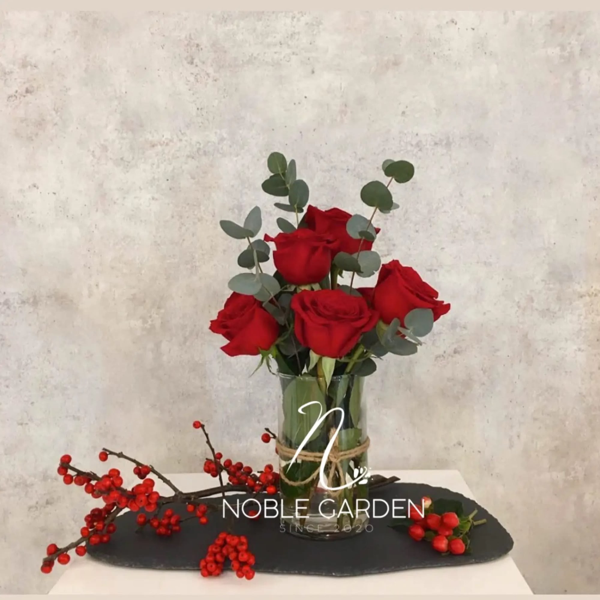 Red roses in a glass vase with eucalyptus stems
