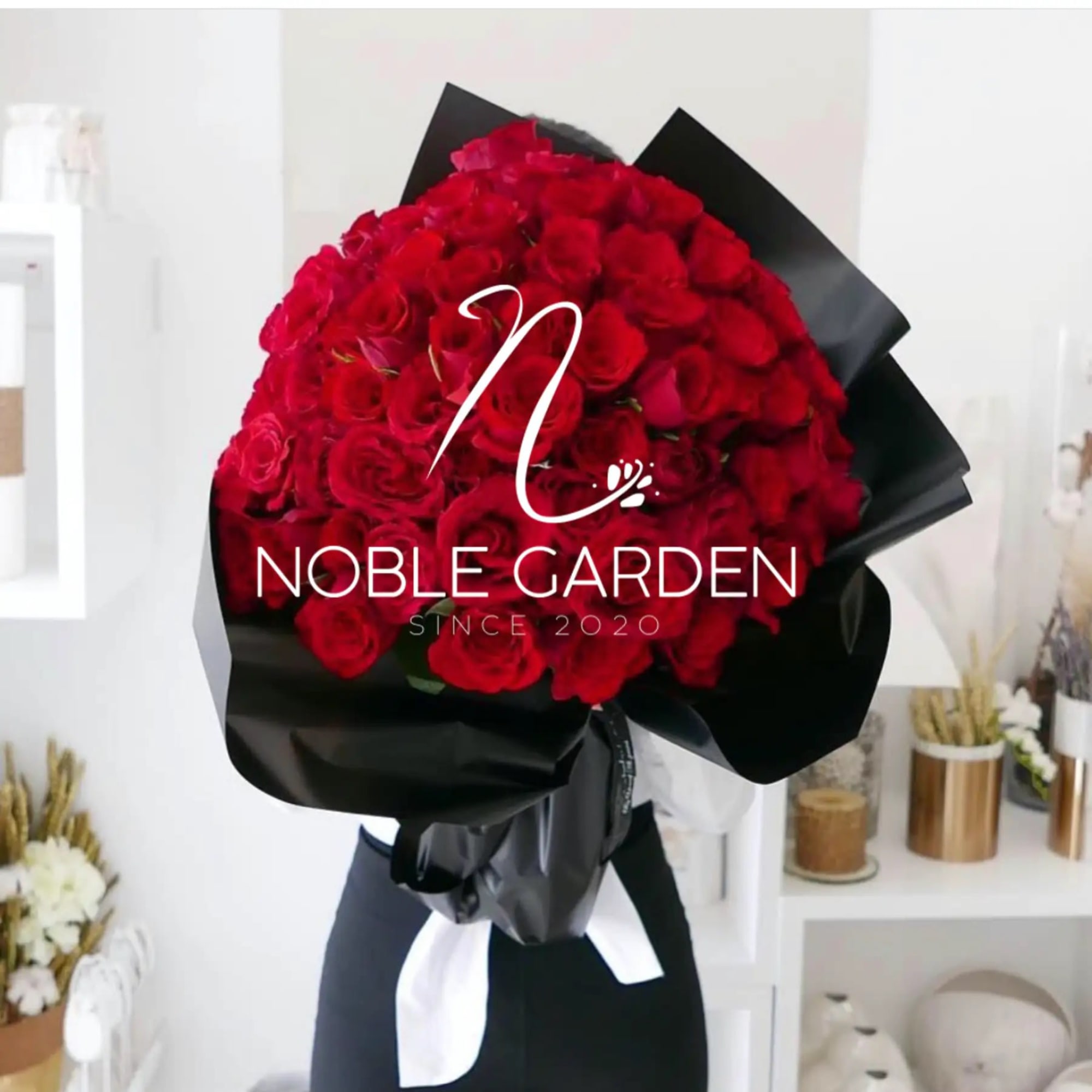 Large bouquet of red roses wrapped in black paper with a white ribbon.