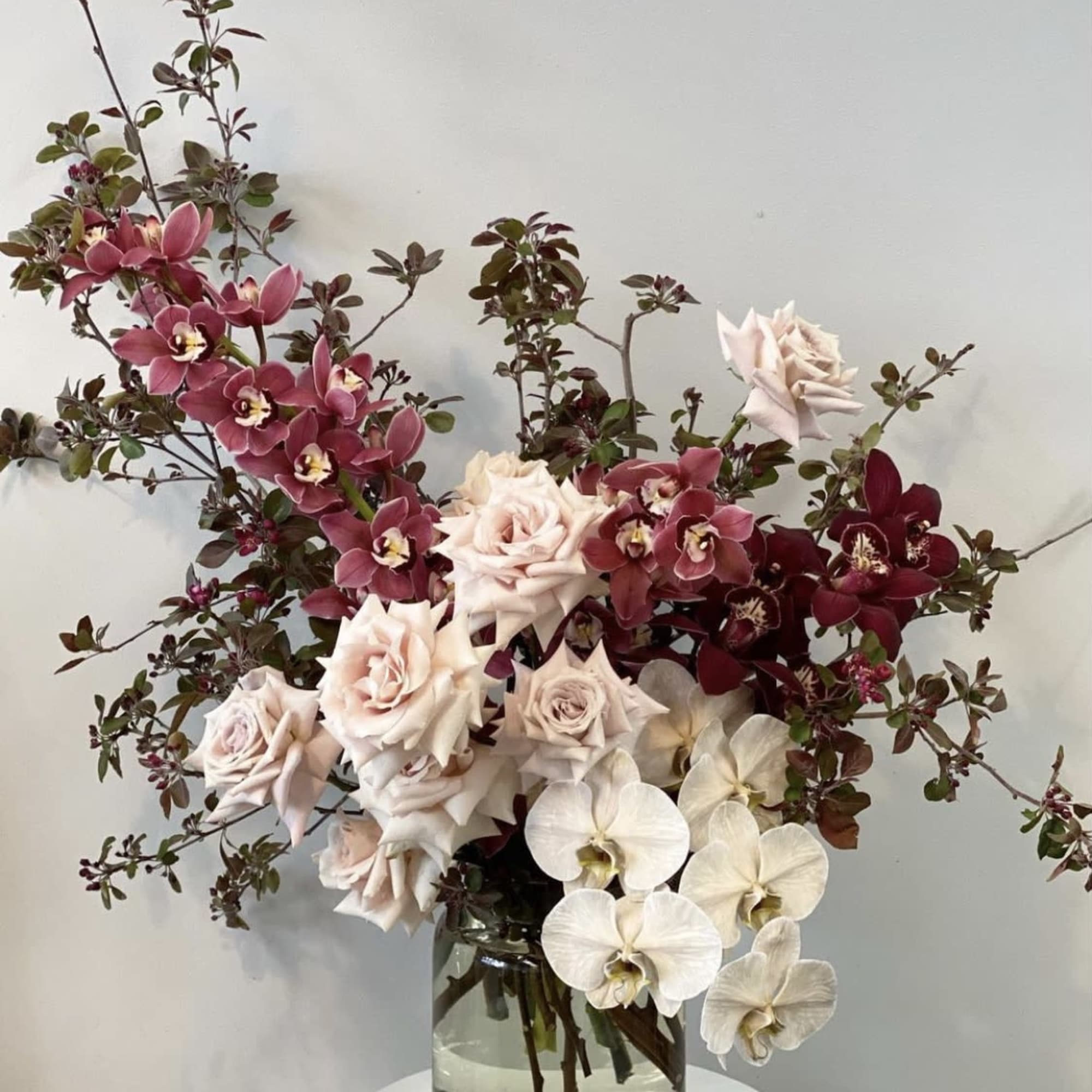 Bouquet of pale roses and orchids in a clear glass vase