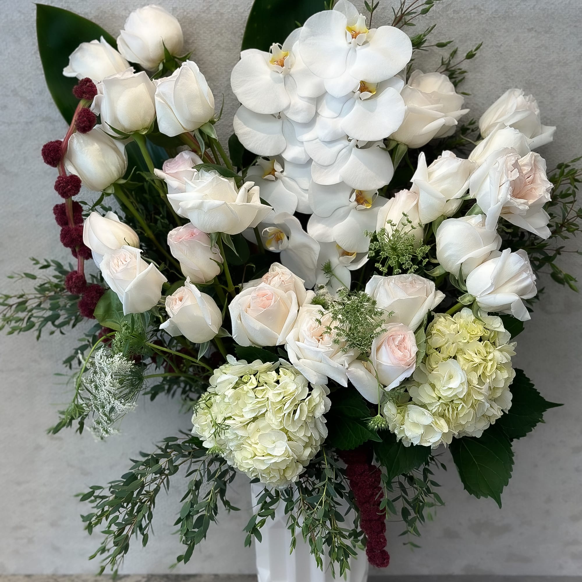 White roses, orchids, and hydrangeas in a white vase