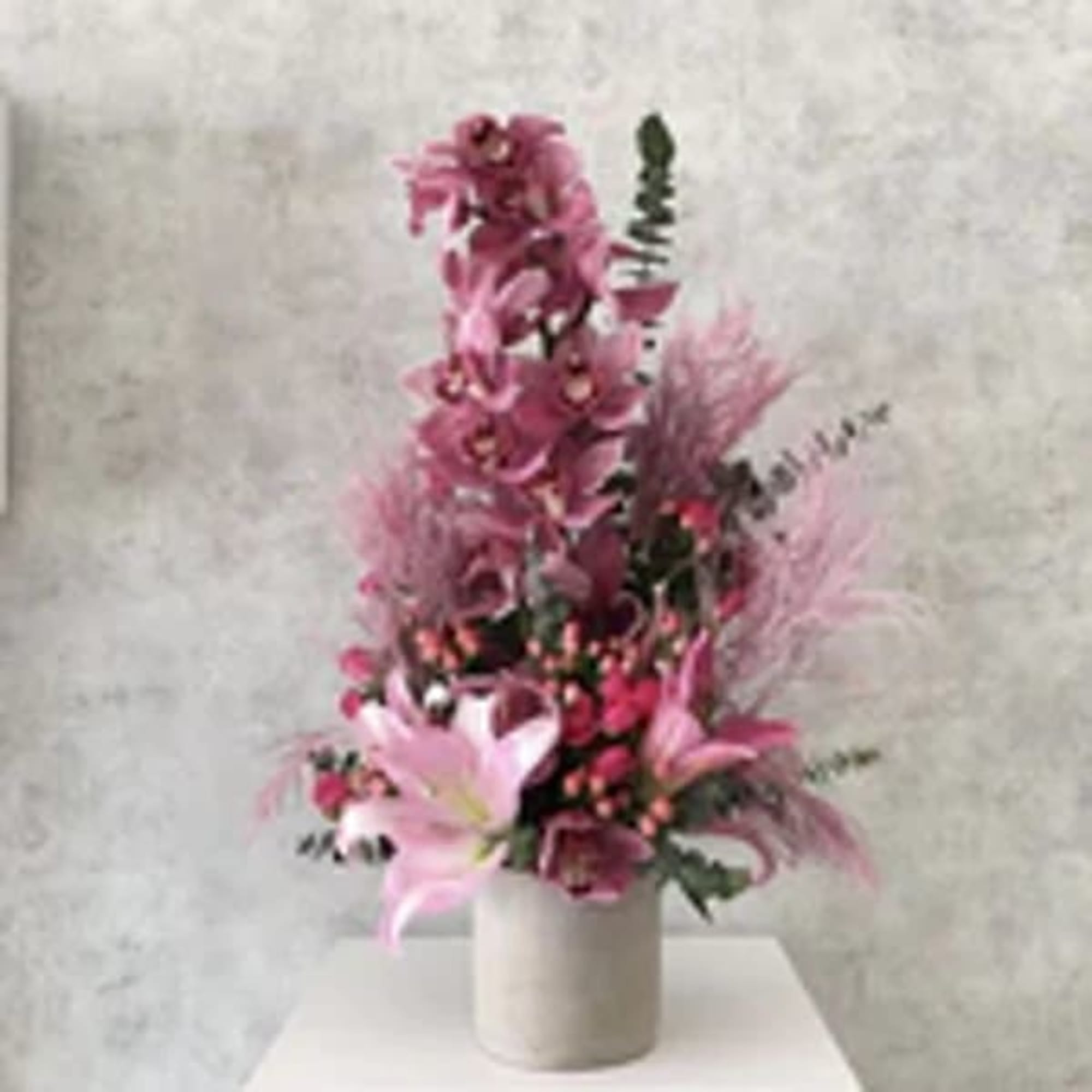 Tall pink floral arrangement in a white vase