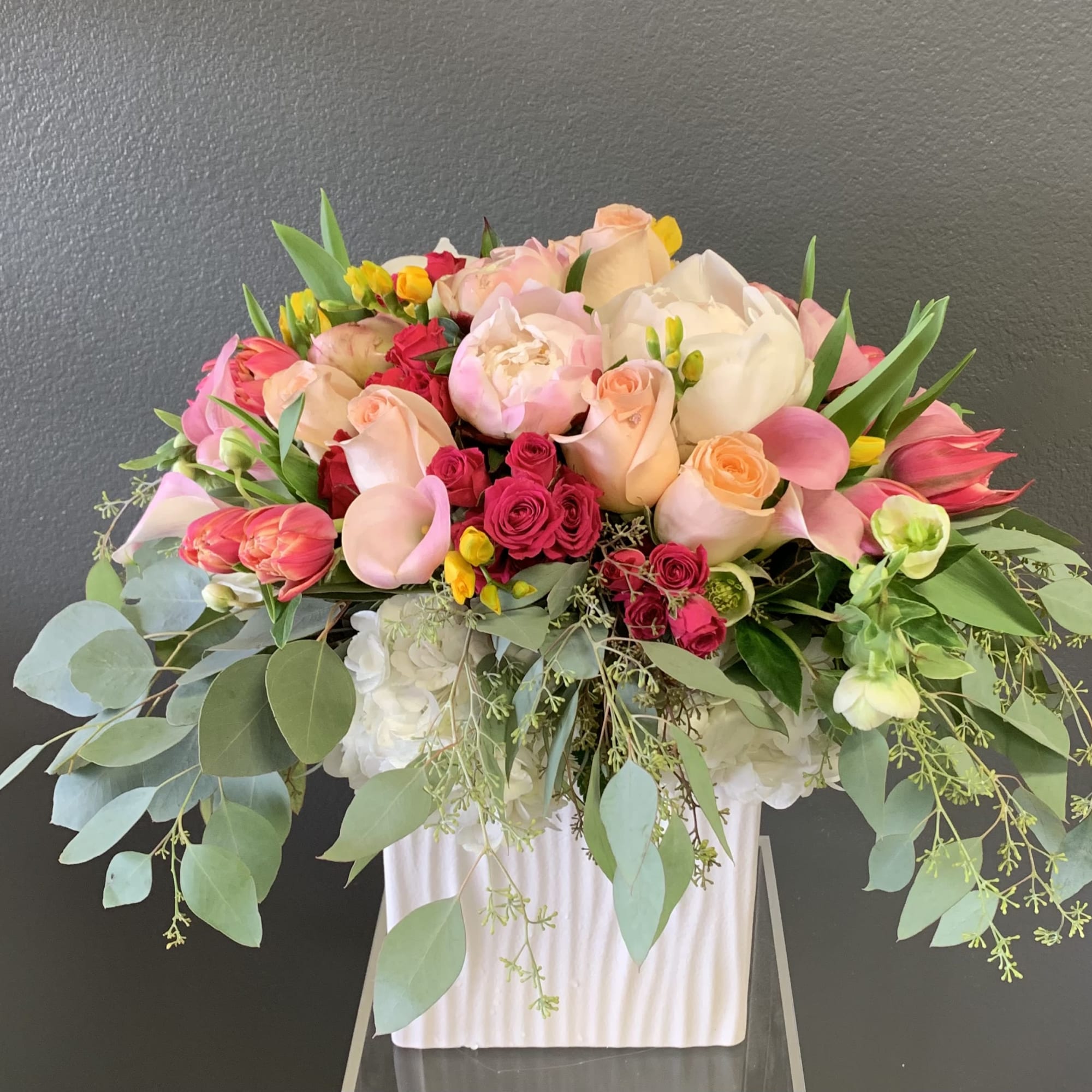 Large bouquet of pink and peach roses with white blooms in a white vase