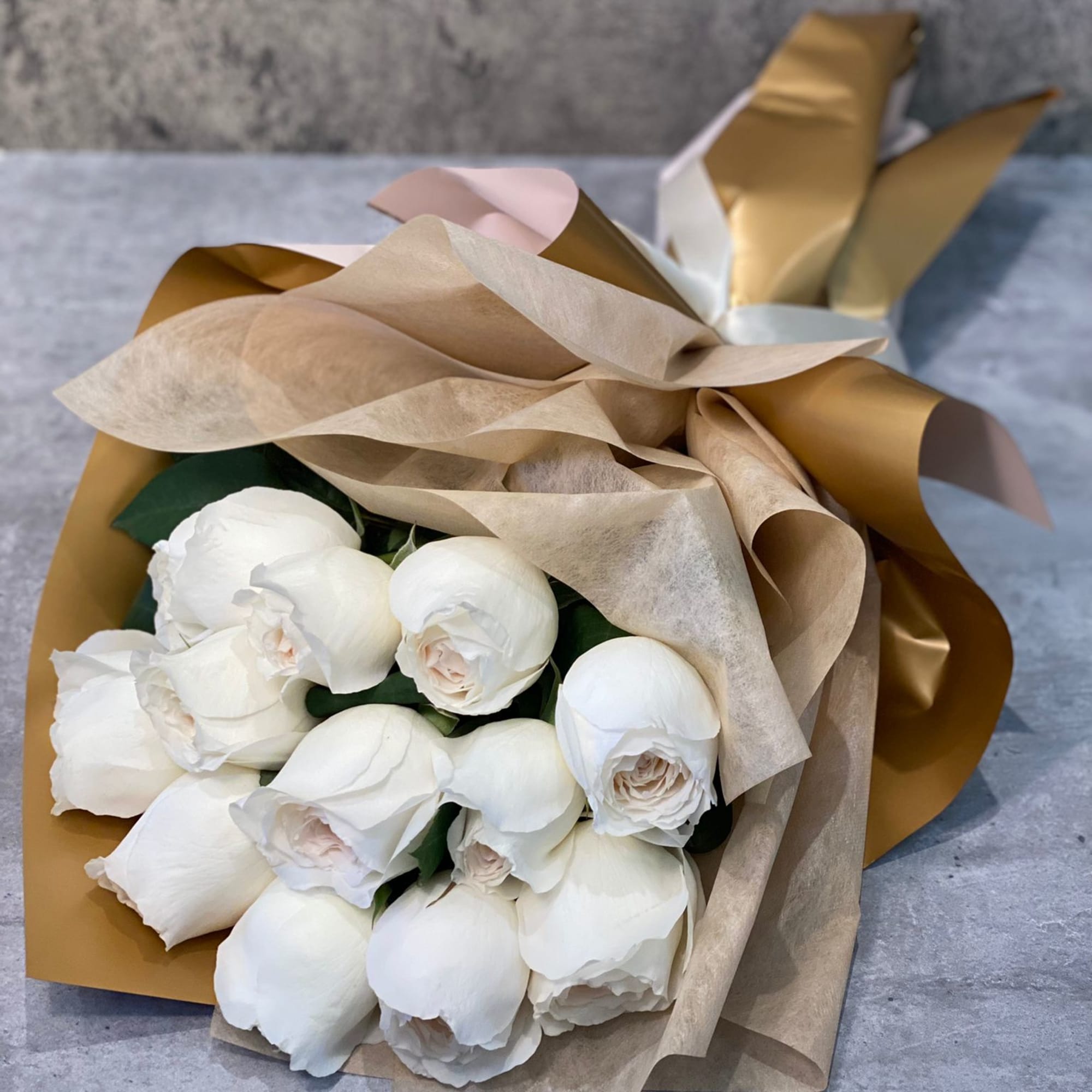 Bouquet of white roses wrapped in tan and gold paper