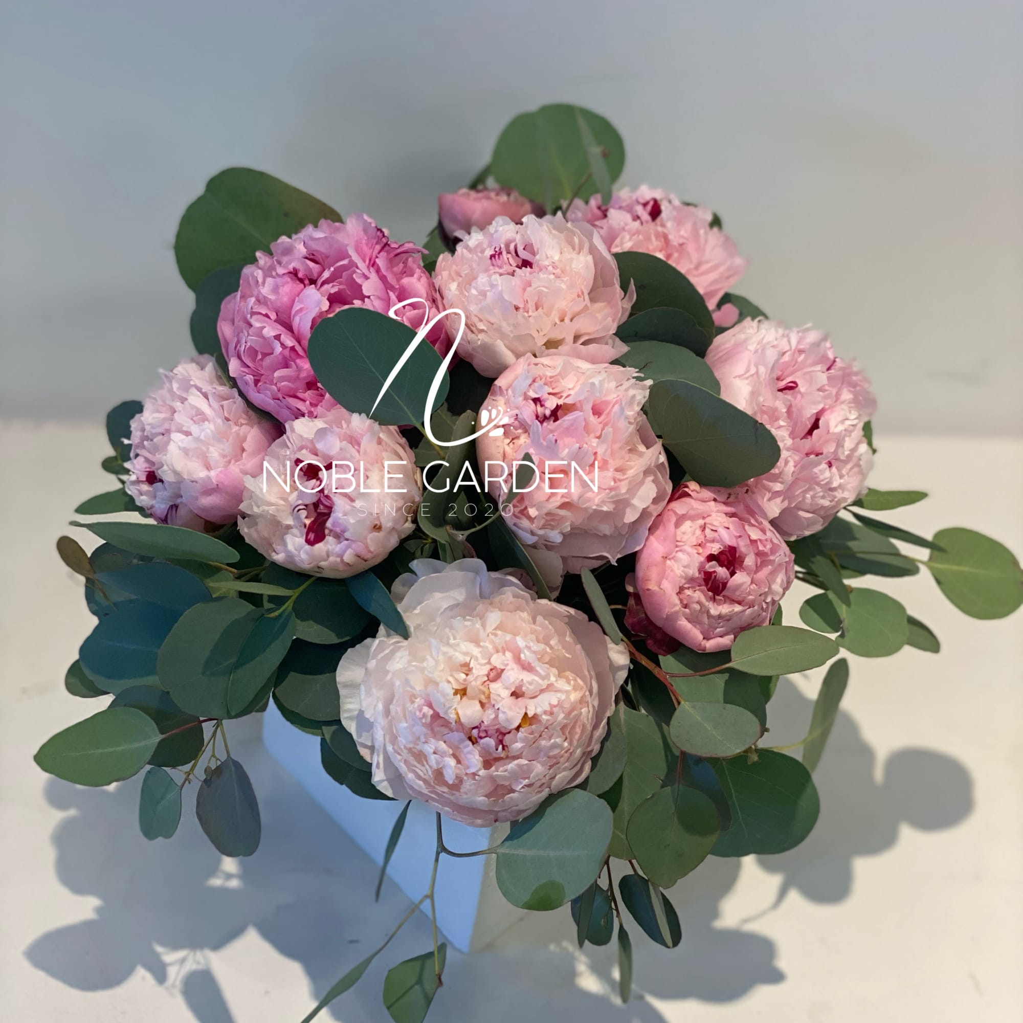 Pink peony bouquet with eucalyptus in a white vase