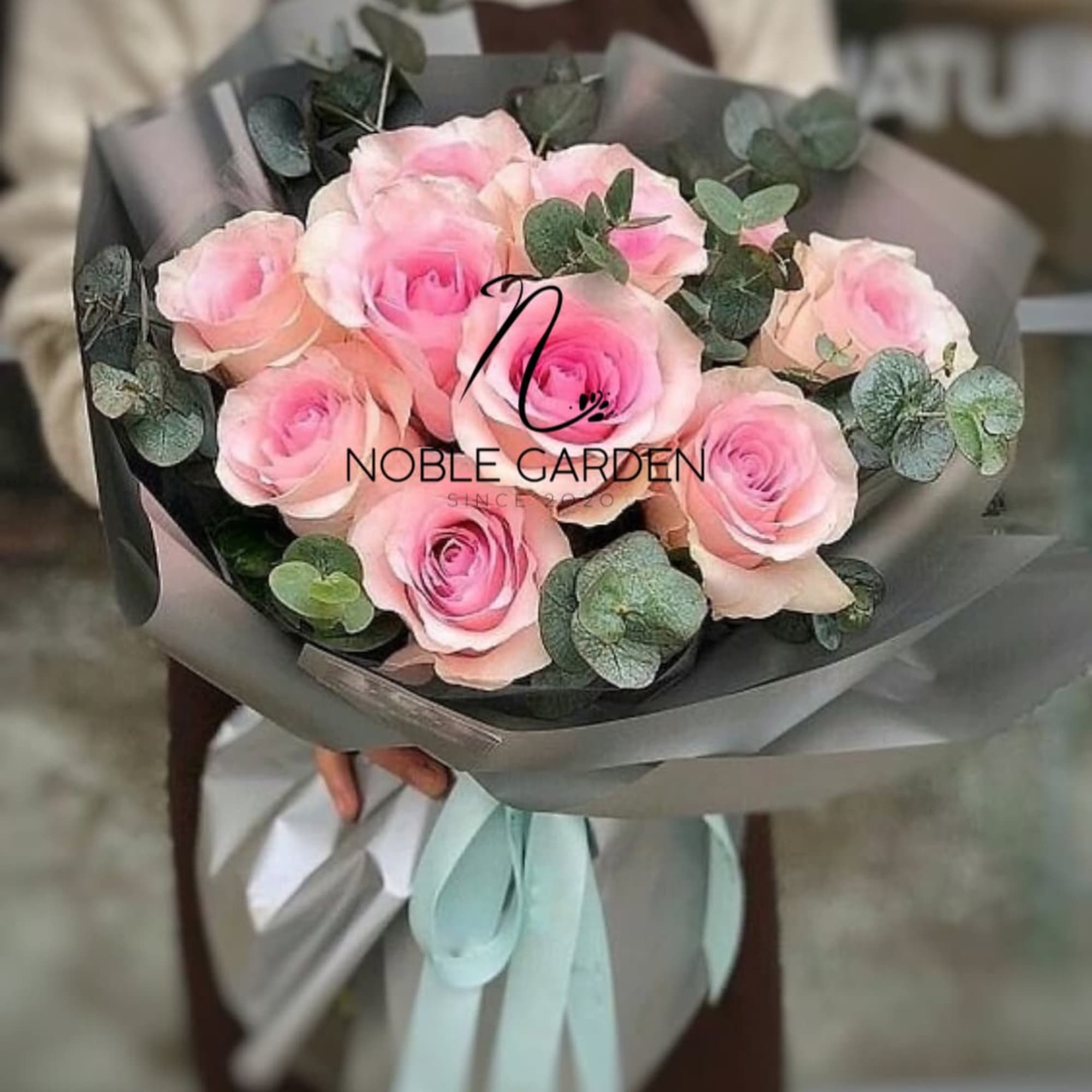 Bouquet of pink roses wrapped in gray paper with eucalyptus